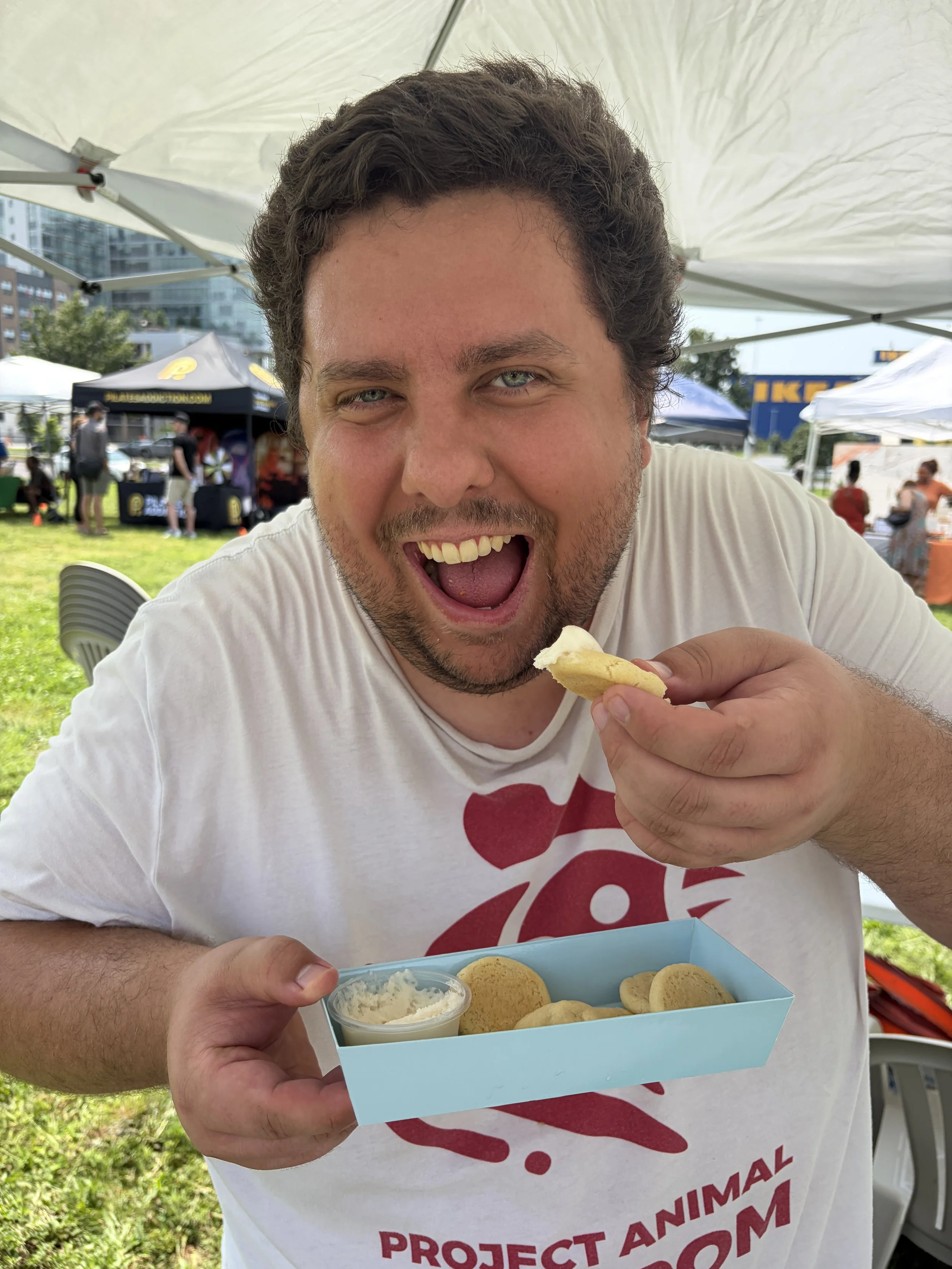 Kyle enjoys plant-based cream cheese frosting sugar cookies from Sweet Treats of St. Louis at STL Vegan Market in St. Louis, Missouri.png