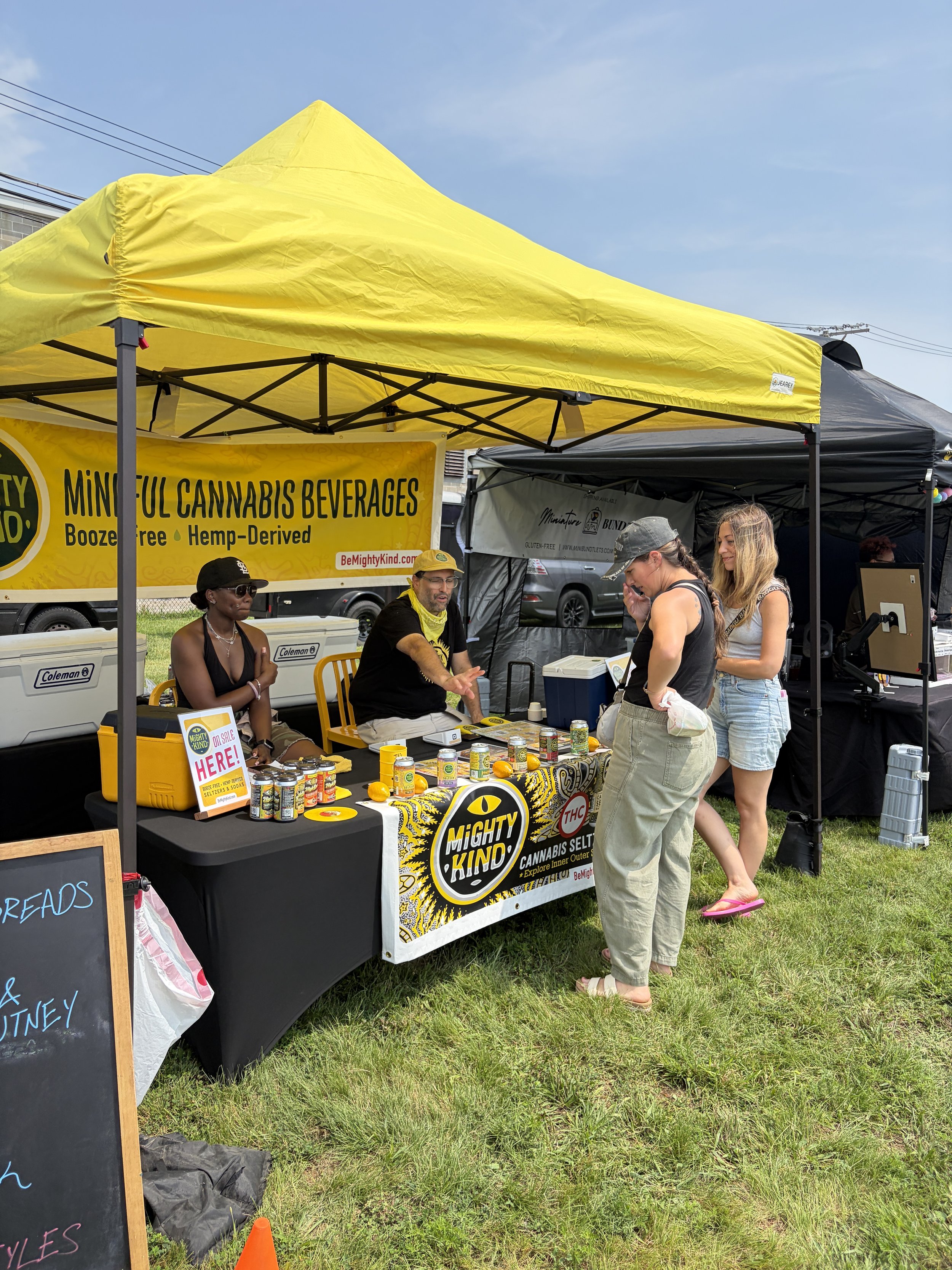 Event attendees decide on drinks at Mighty Kind_s booth at STL Vegan Market in St. Louis, Missouri.png