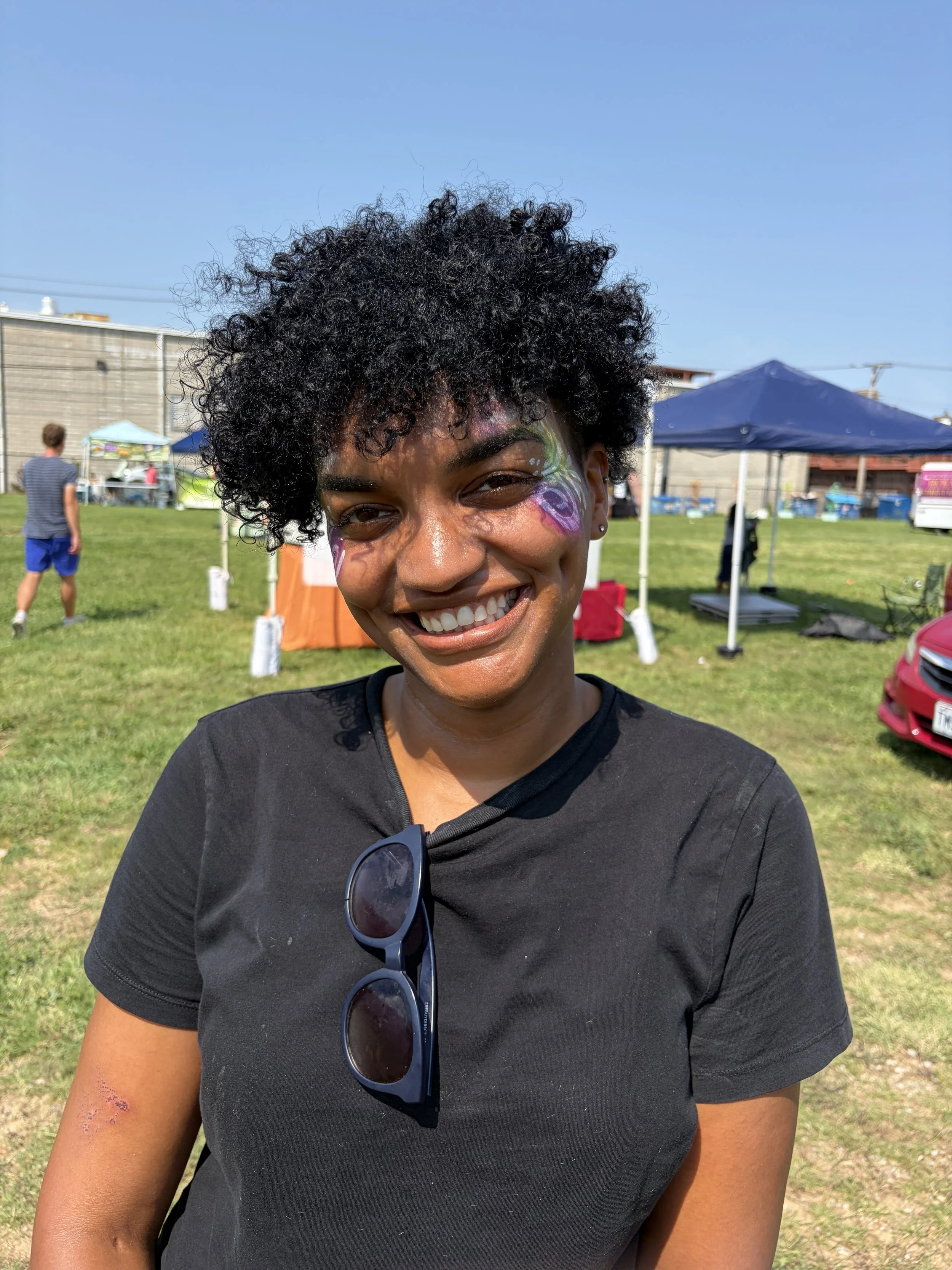 Face-painted attendee smiles at STL Vegan Market in St. Louis, Missouri outside of Hannah_s booth.png