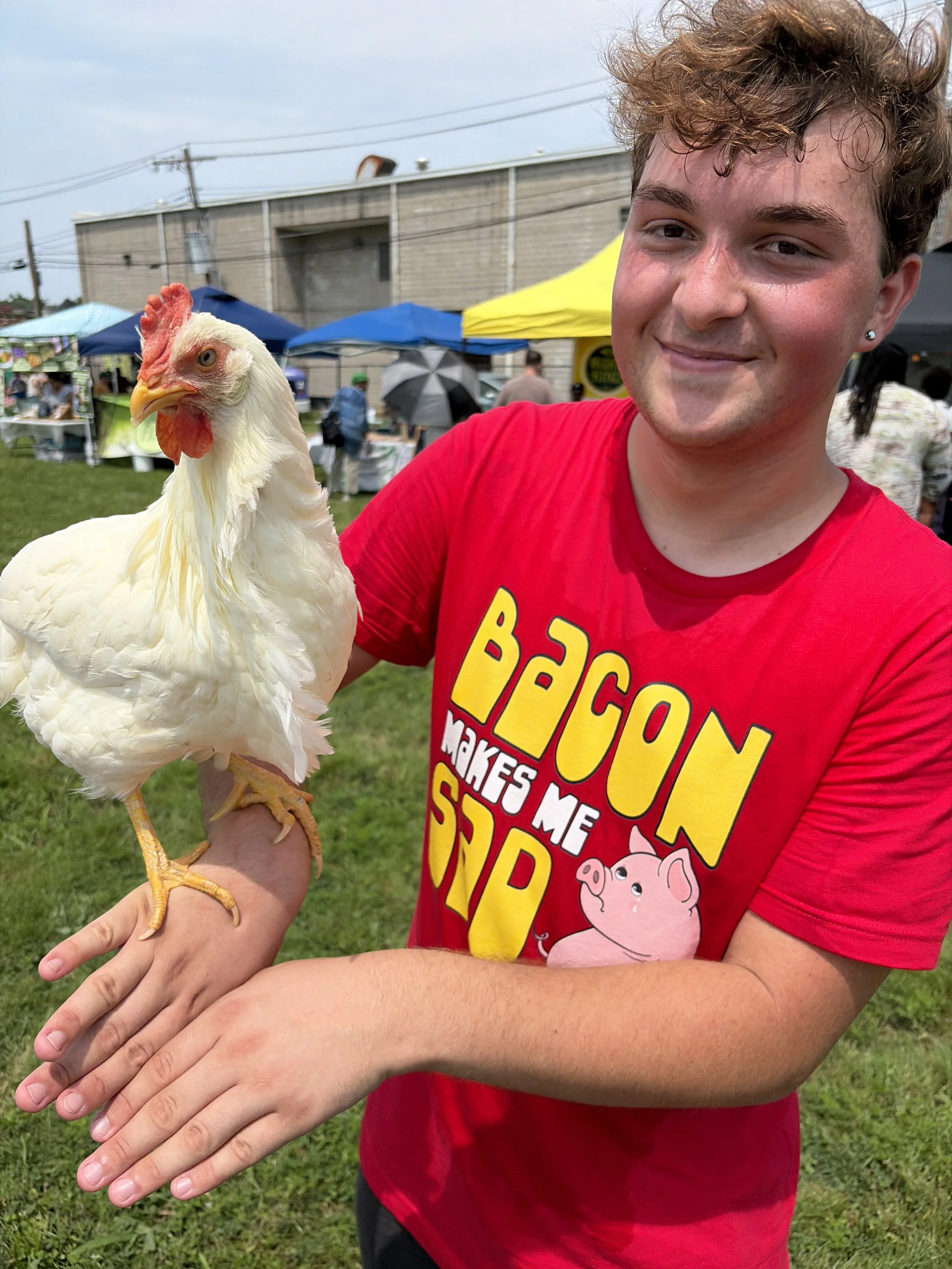 Troy happily holds Spike while wearing a Bacon Makes Me Sad shirt at STL Vegan Market in St. Louis, Missouri.png