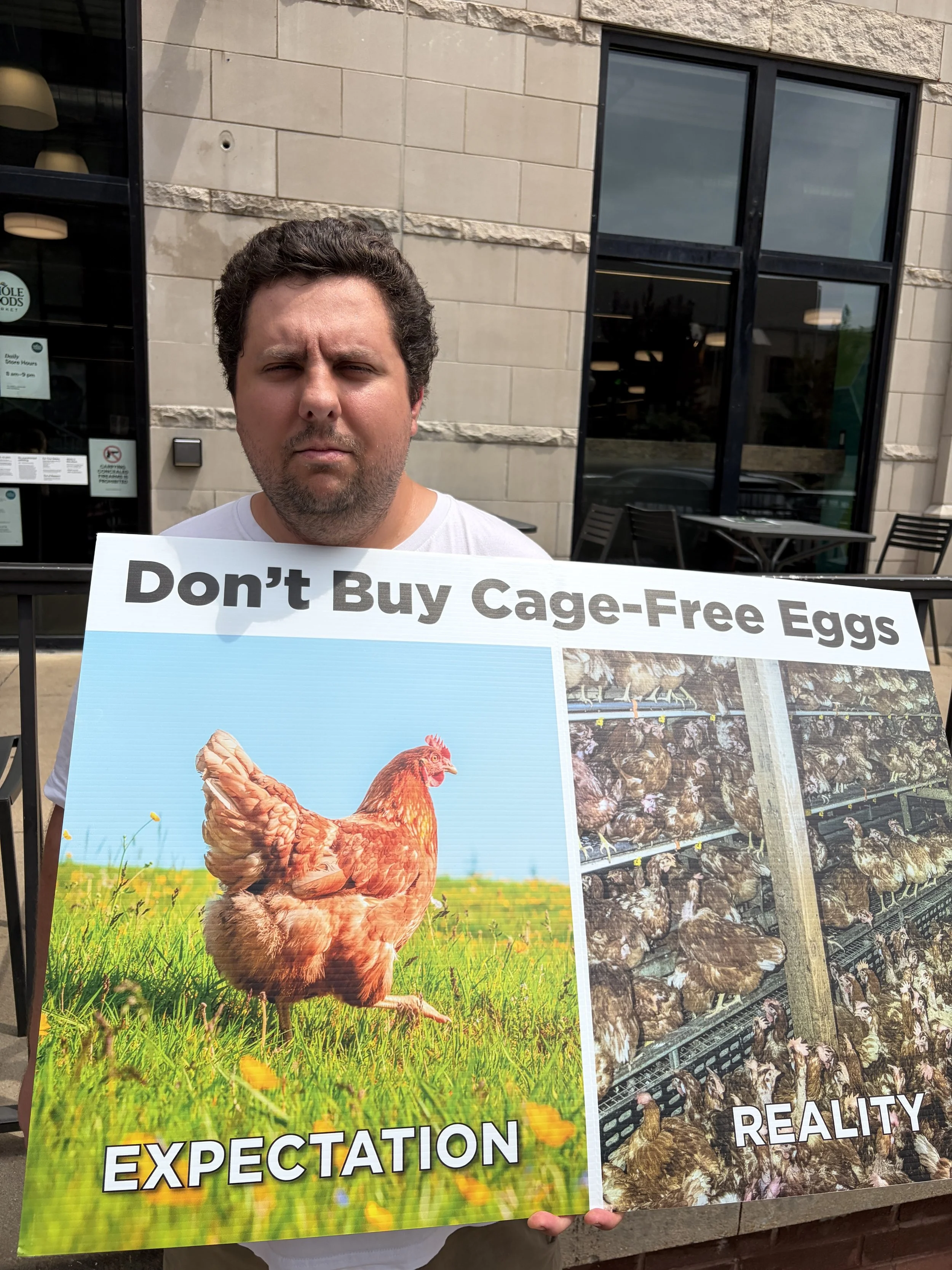Kyle holds up Don_t Buy Cage-Free Eggs sign at Whole Foods in St. Louis, Missouri.png