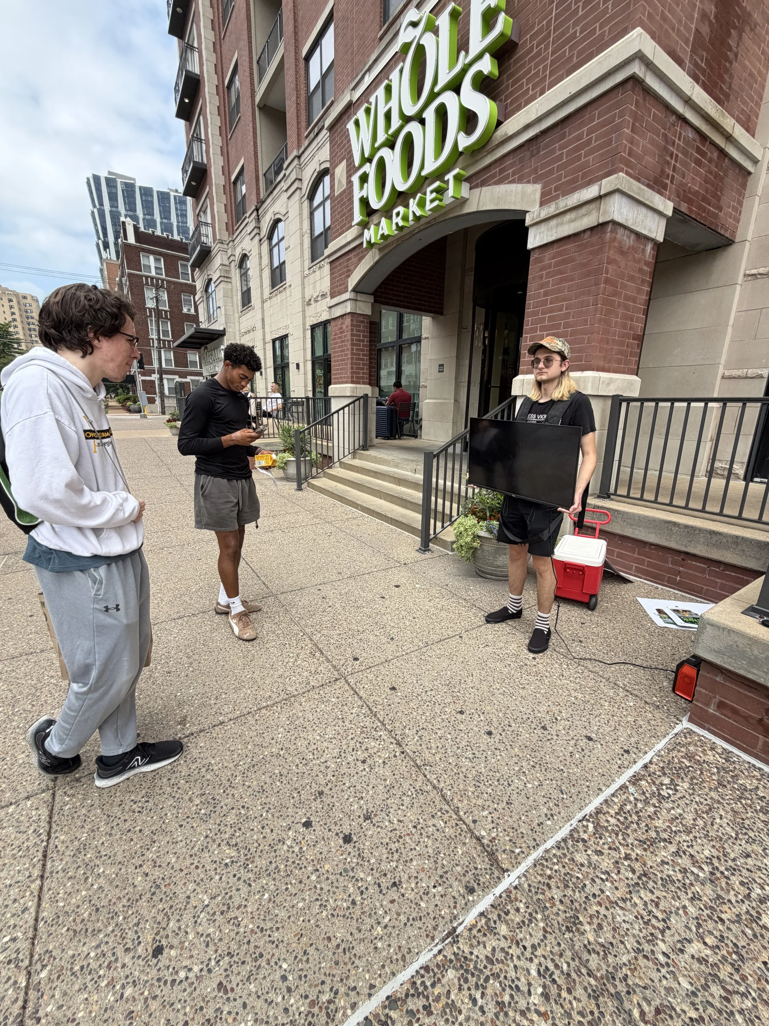 Person watches the footage of chickens at cage-free egg farms at Whole Foods Egg-spose in St. Louis, Missouri.png