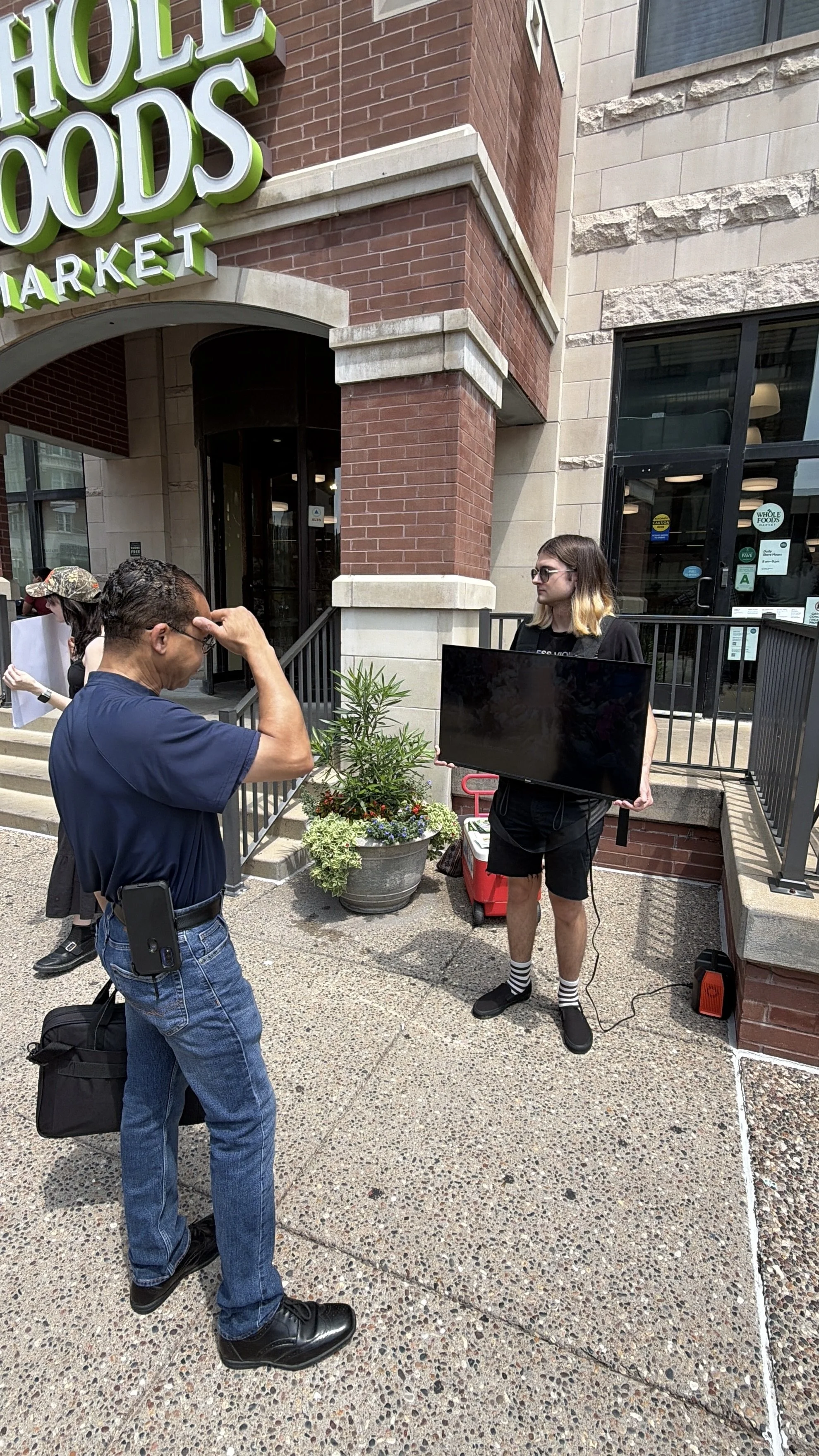 Passerby watches footage of cage-free eggs at Whole Foods Egg-spose in St. Louis, Missouri.png