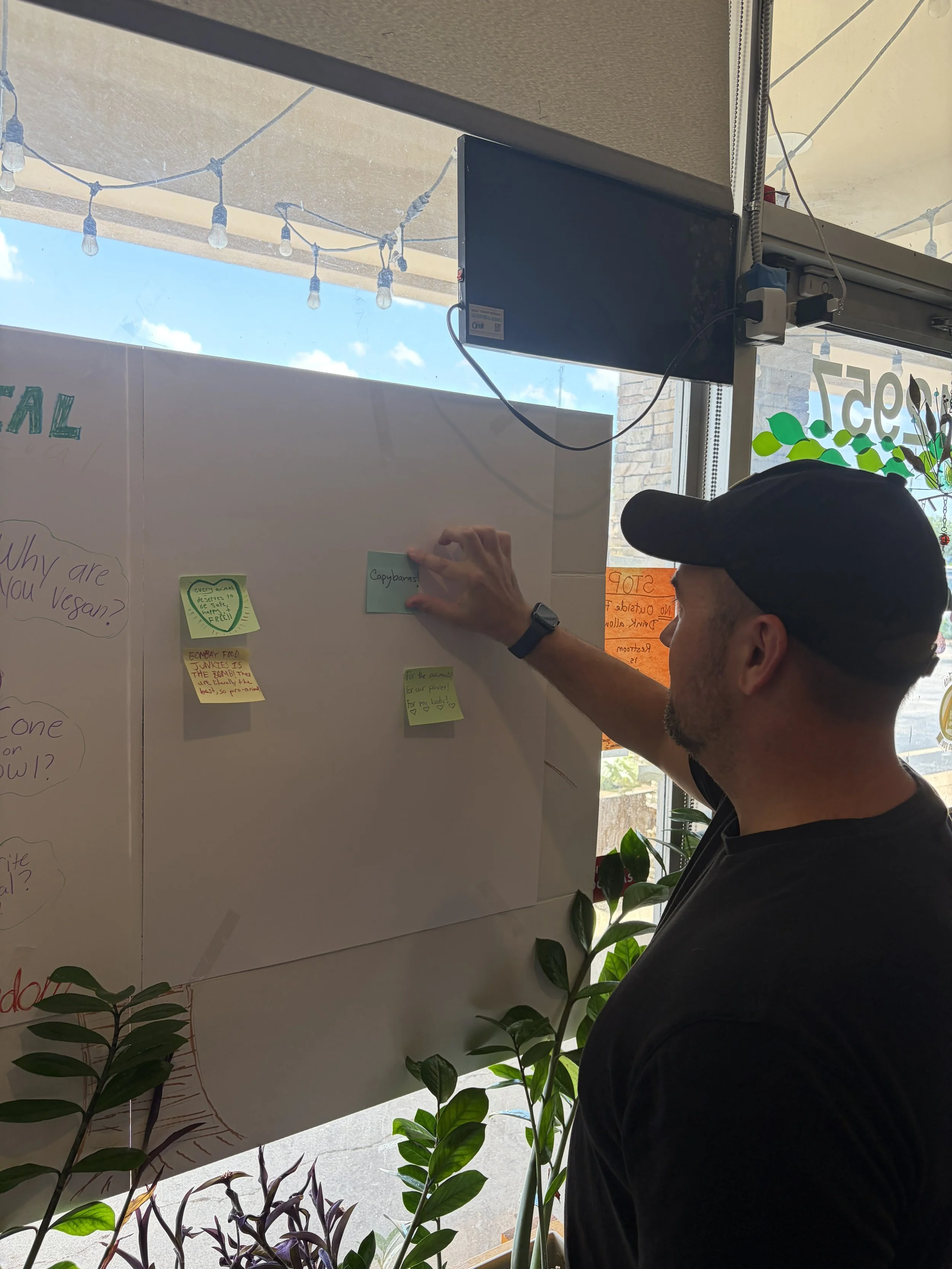 Dan places a positive note on poster board at Vegan Ice Cream Social at Bombay Food Junkies in St. Louis, Missouri.png