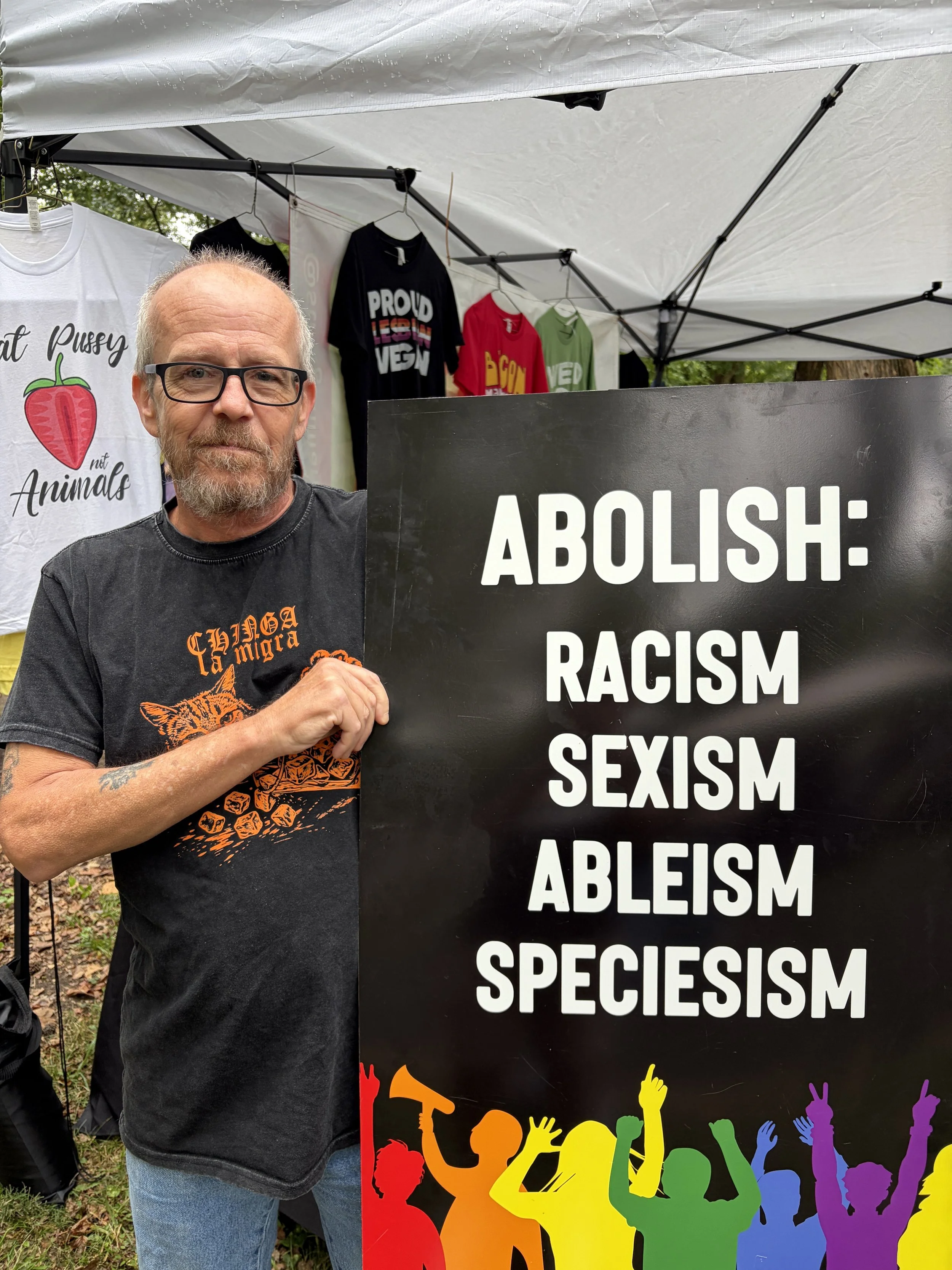Guest of Vegan Pride Booth at Tower Grove Pride holds sign in St. Louis, Missouri.png
