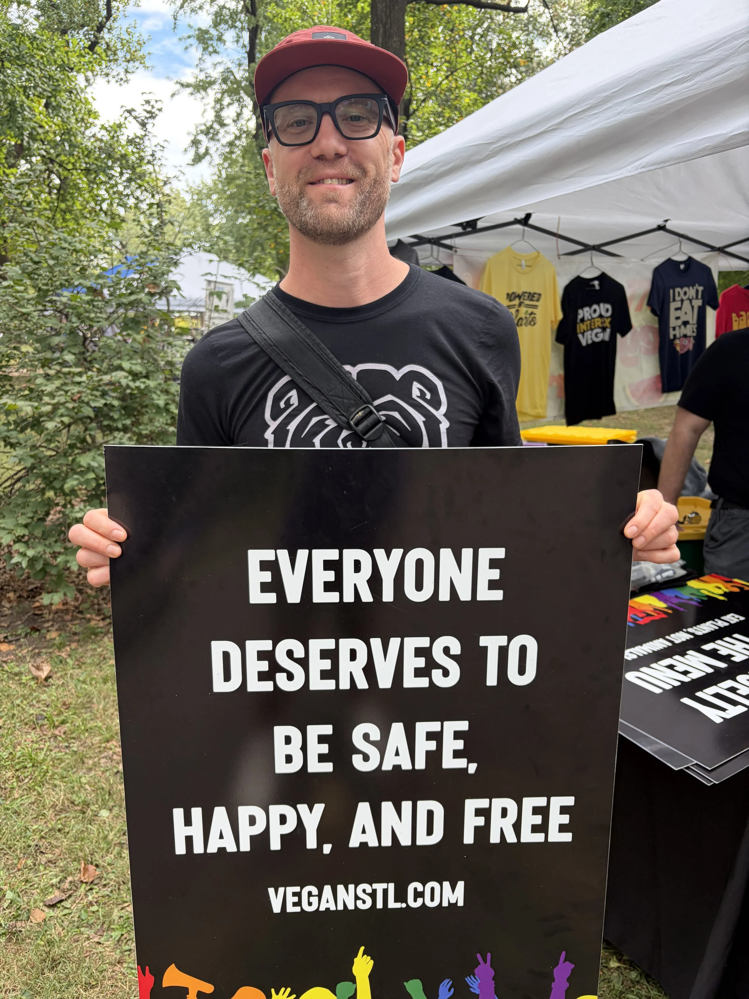 Vegan Pride Booth at Tower Grove Pride booth guest holds sign in St. Louis, Missouri.png