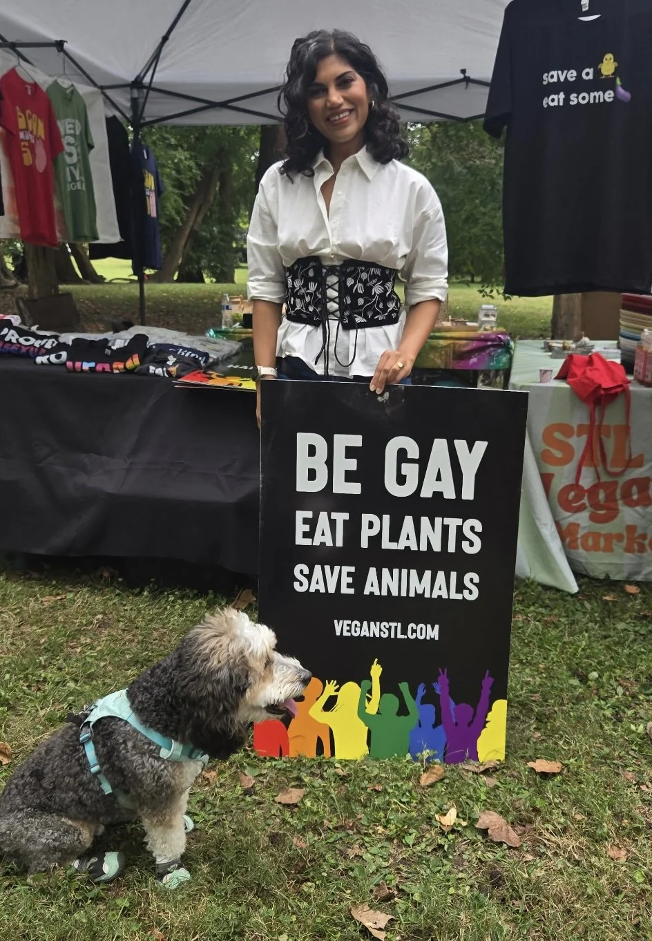 Karishma holds a Be Gay Eat Plants sign at Vegan Pride Booth at Tower Grove Pride in St. Louis, Missouri.png