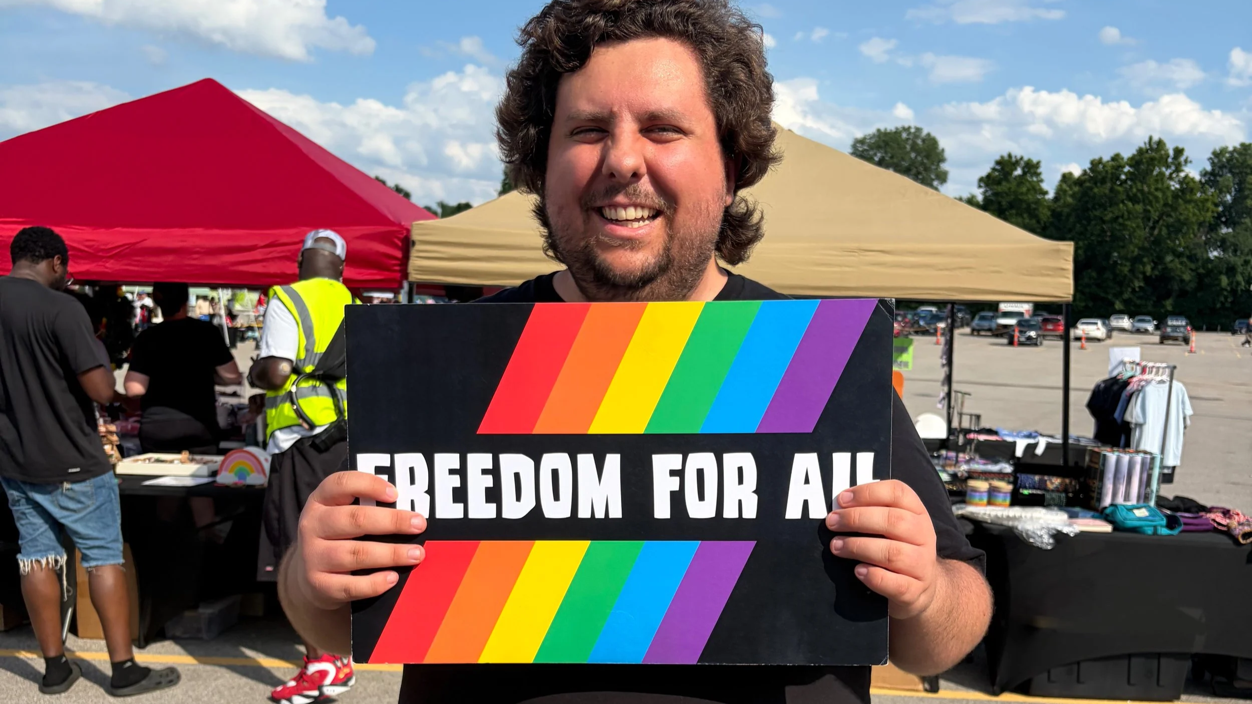 Kyle Luzynski, a vegan animal rights activist and founder of Project Animal Freedom, holding a sign that reads freedom for all at Pride St. Charles
