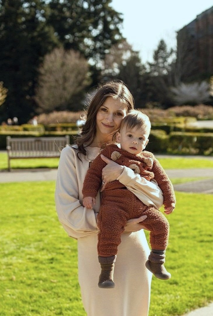 Woman holding a baby in a park under sunlight