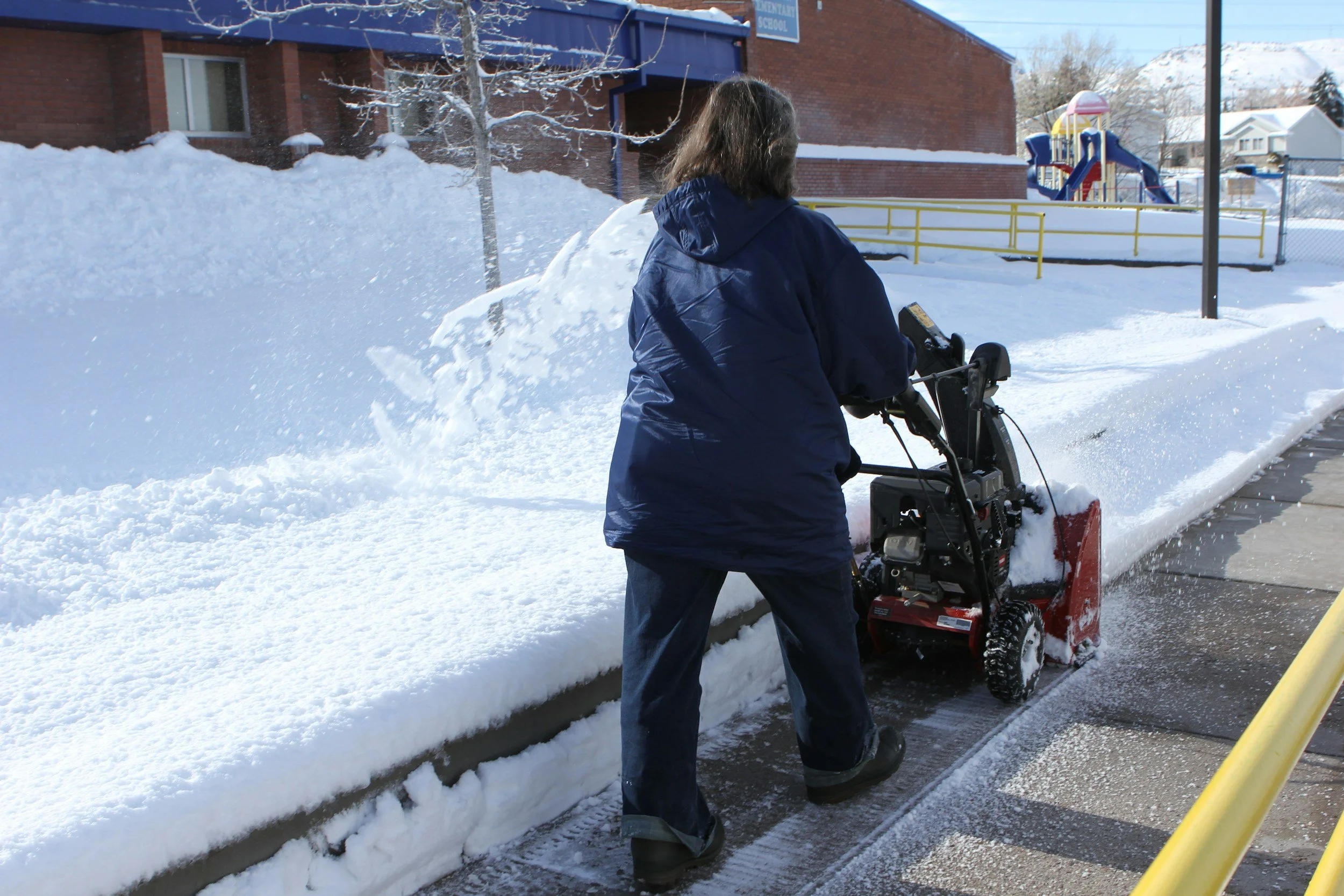 Worker clearing snow from a commercial walkway