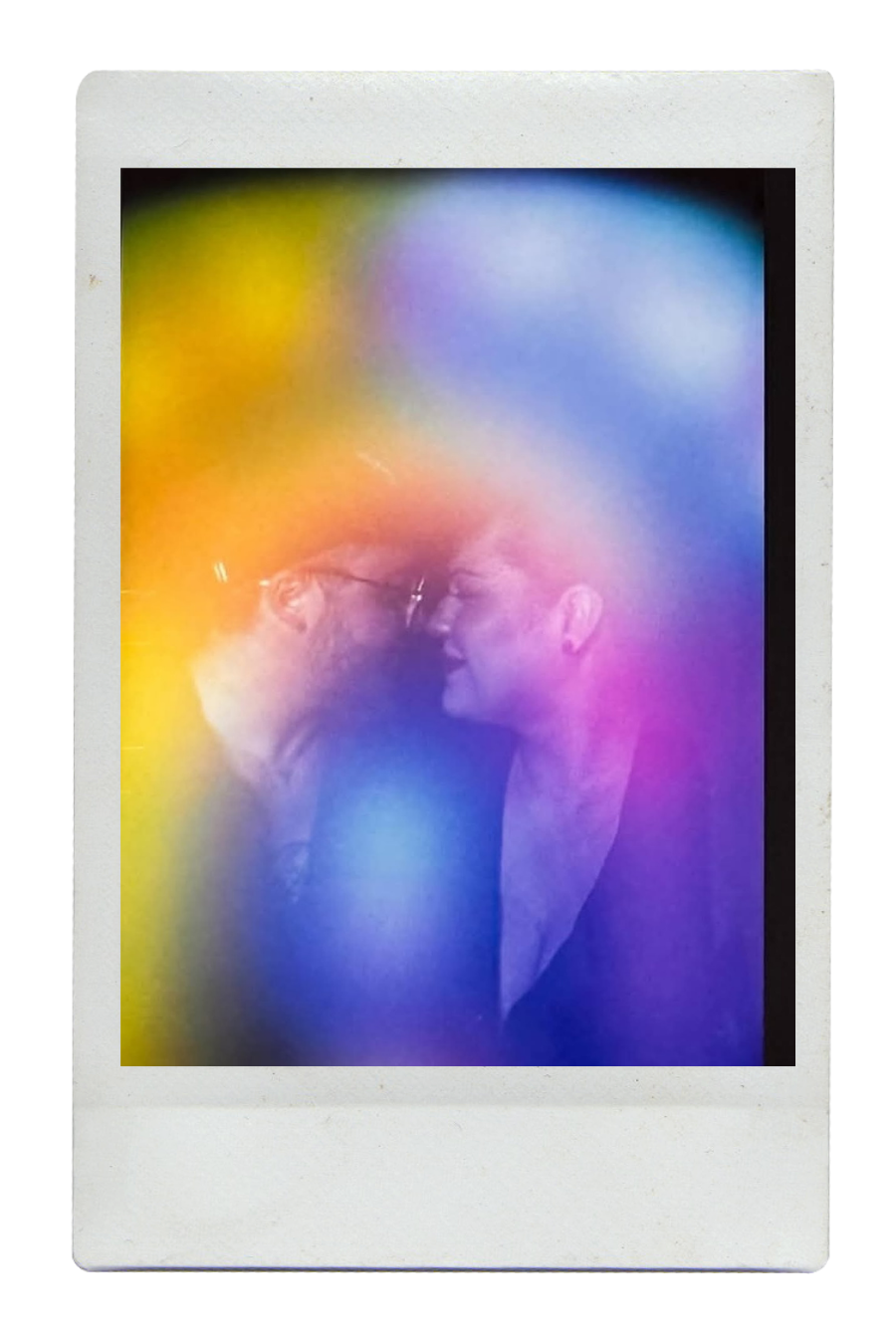 Two people face each other with foreheads touching, smiling, and surrounded by colorful, blurred light effects.