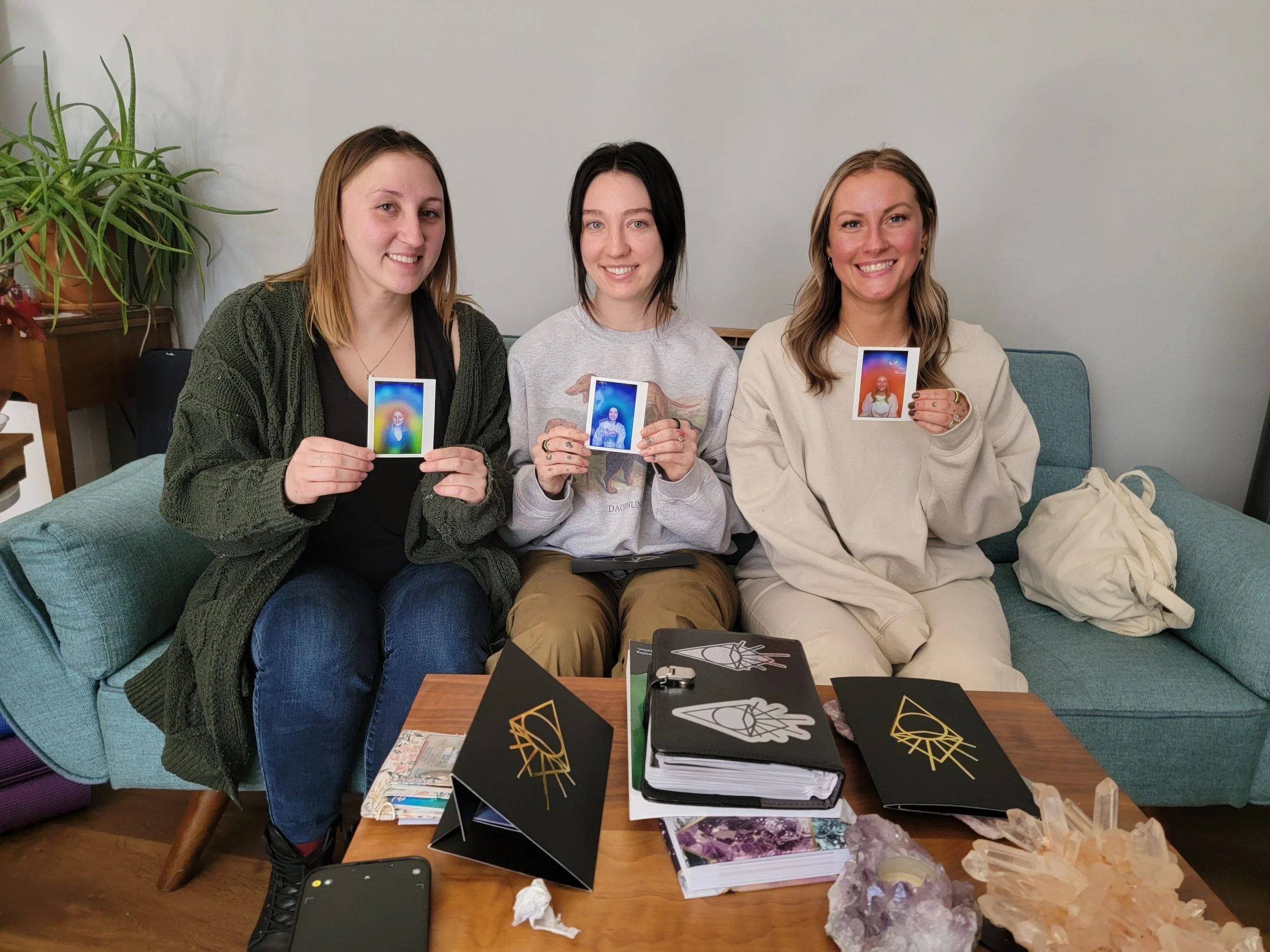 Group of three people holding their aura photos while sitting on the couch in the studio.
