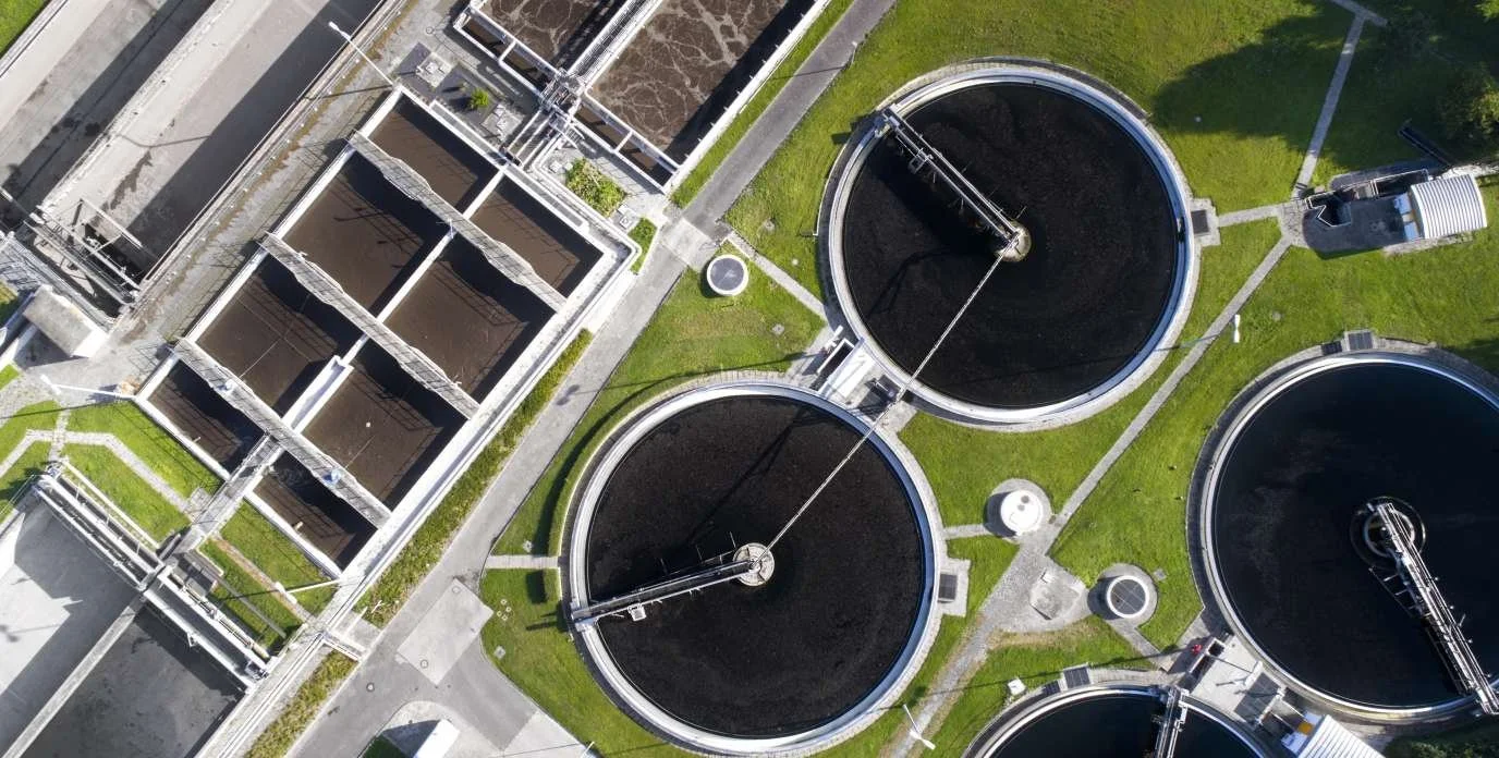Wastewater treatment plant with large circular and rectangular tanks. Pump station, booster station, rotary screen, belt press, instruments and sensors.