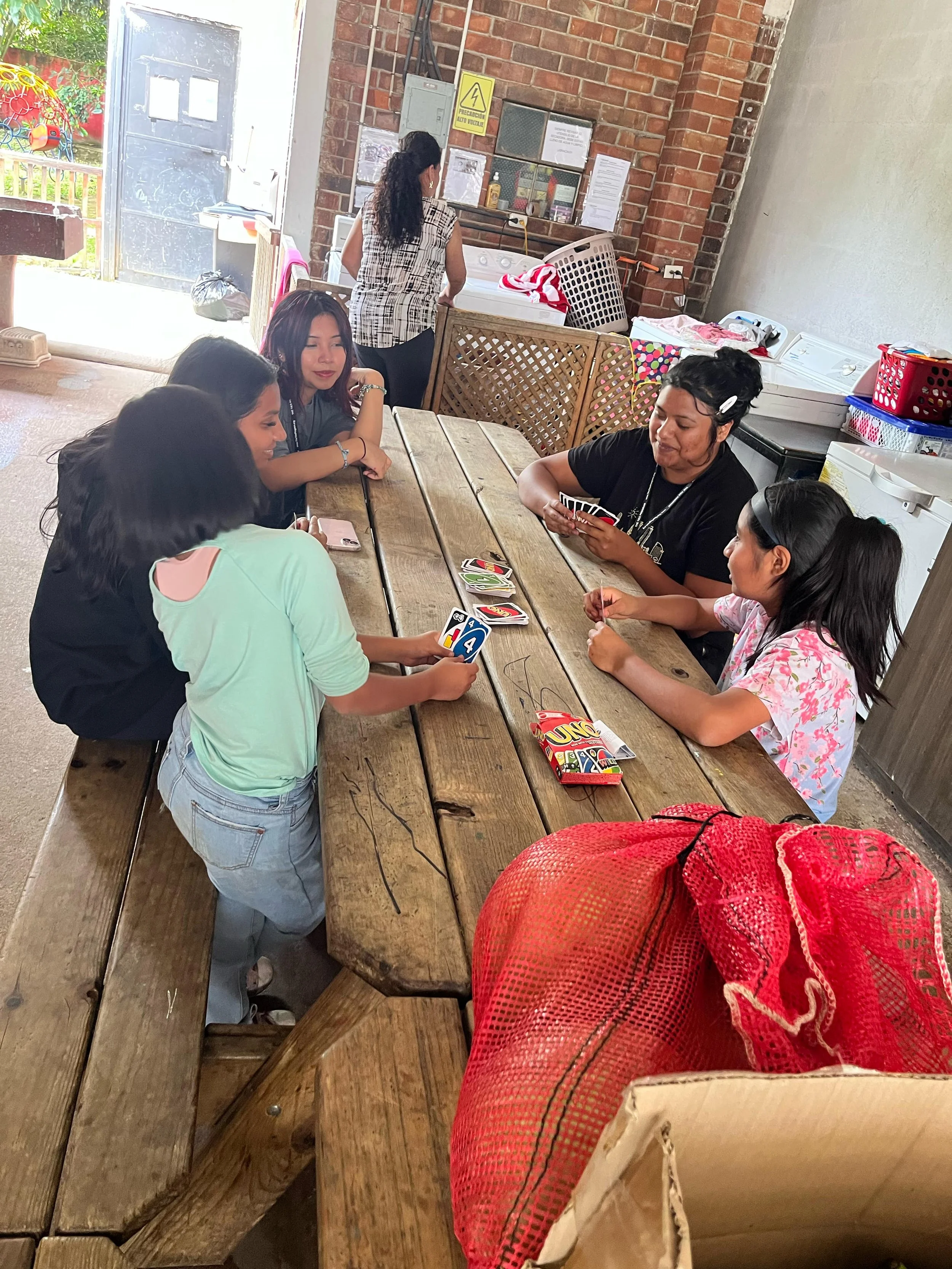 A young Guatemalan woman showing Guatemalan children the game of Uno.