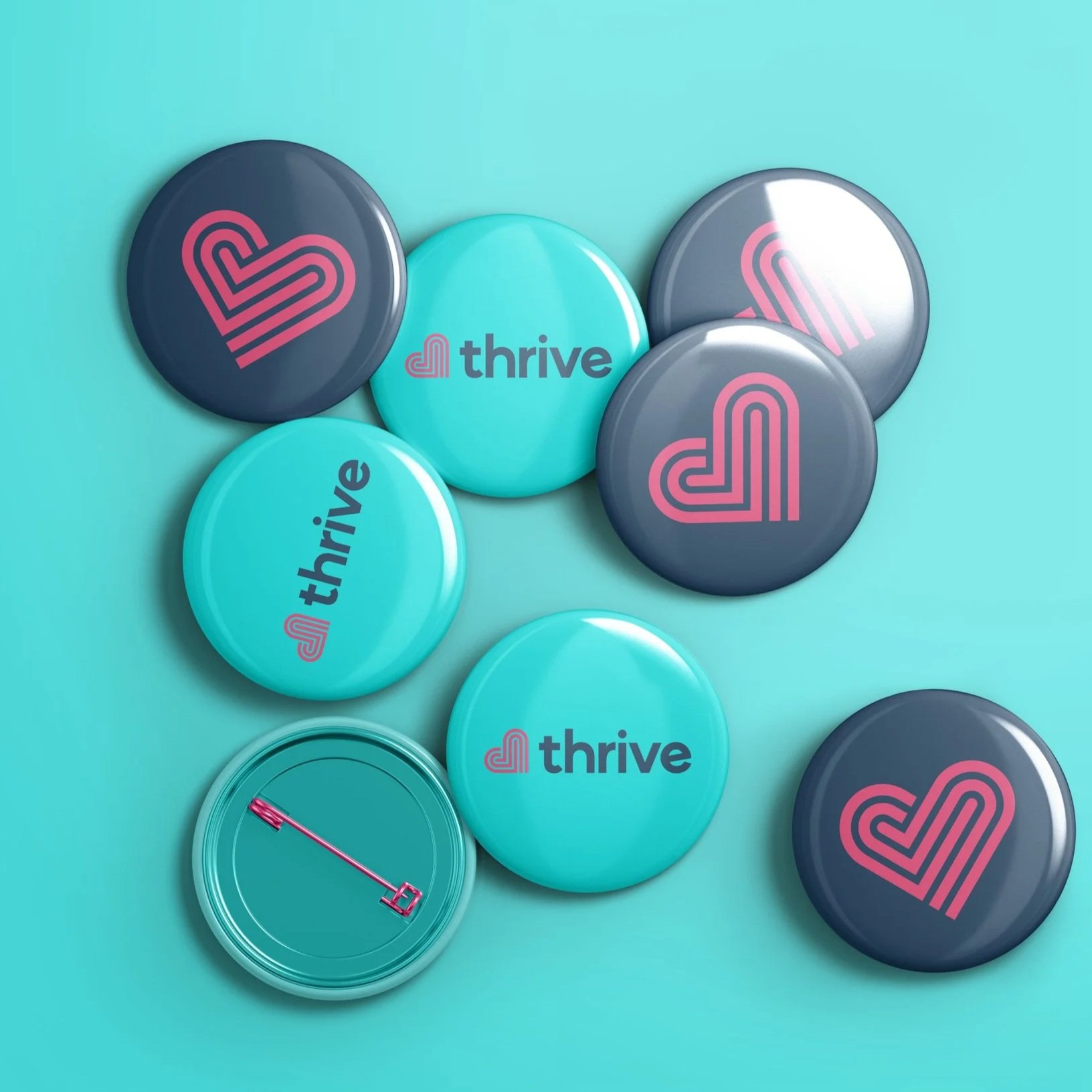 Button pins with Thrive logo and text on a light blue surface