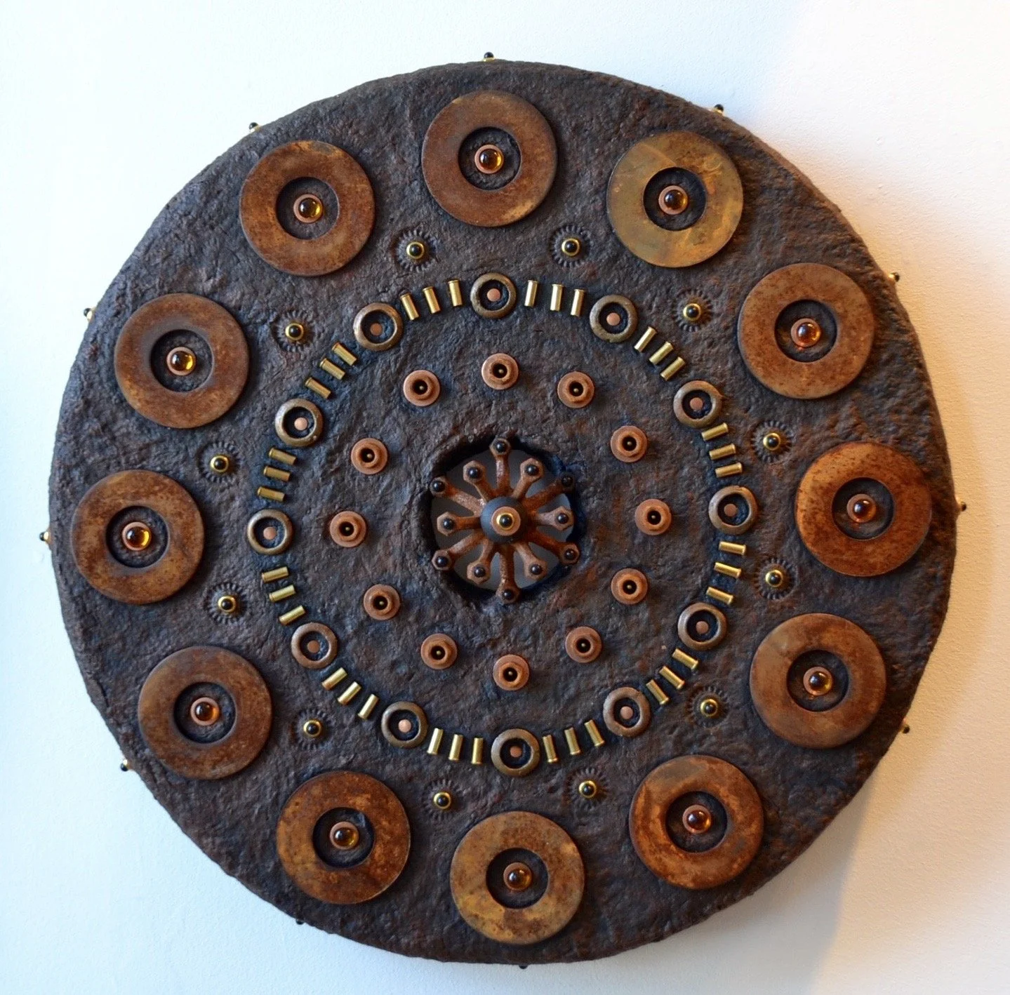 GOING AROUND IN CIRCLES - Mixed media, paper pulp; iron, brass and copper washers; brass shell casings, glass beads, map pins.
(22”diameter x 3”d)