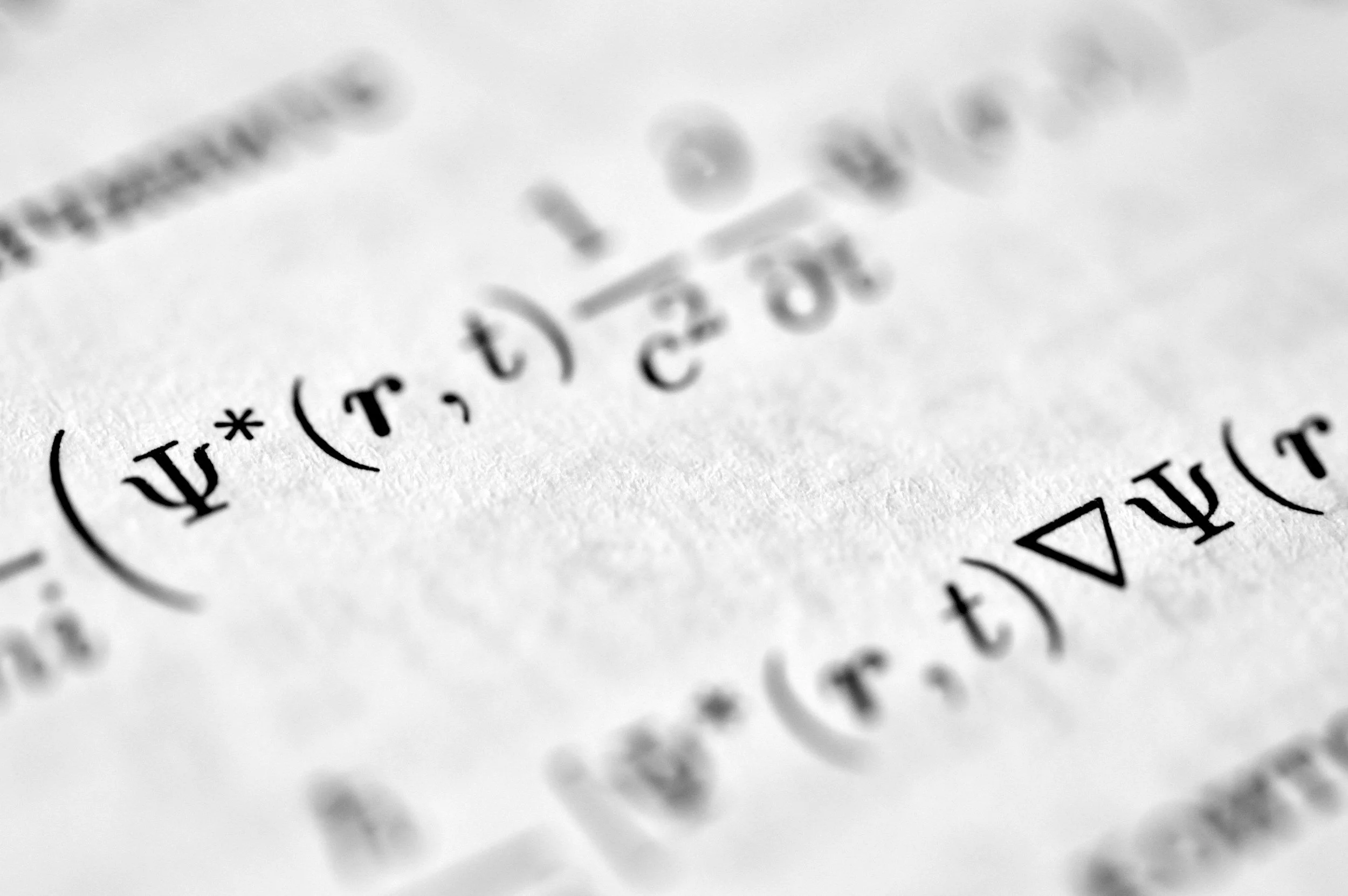 Close-up of a printed mathematical equation on white paper, showing integral and Greek symbols.