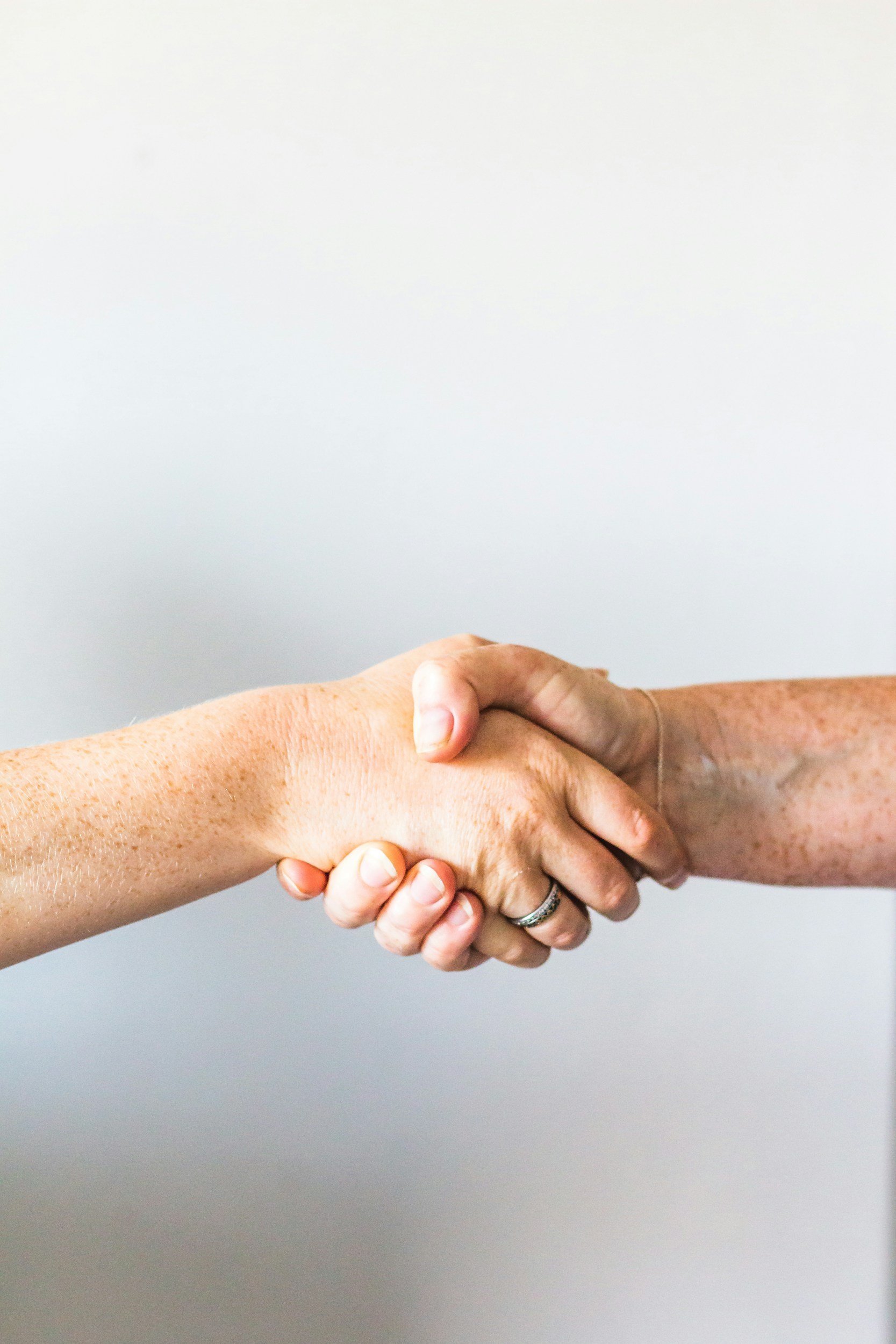 Two hands shaking in front of a plain white background.