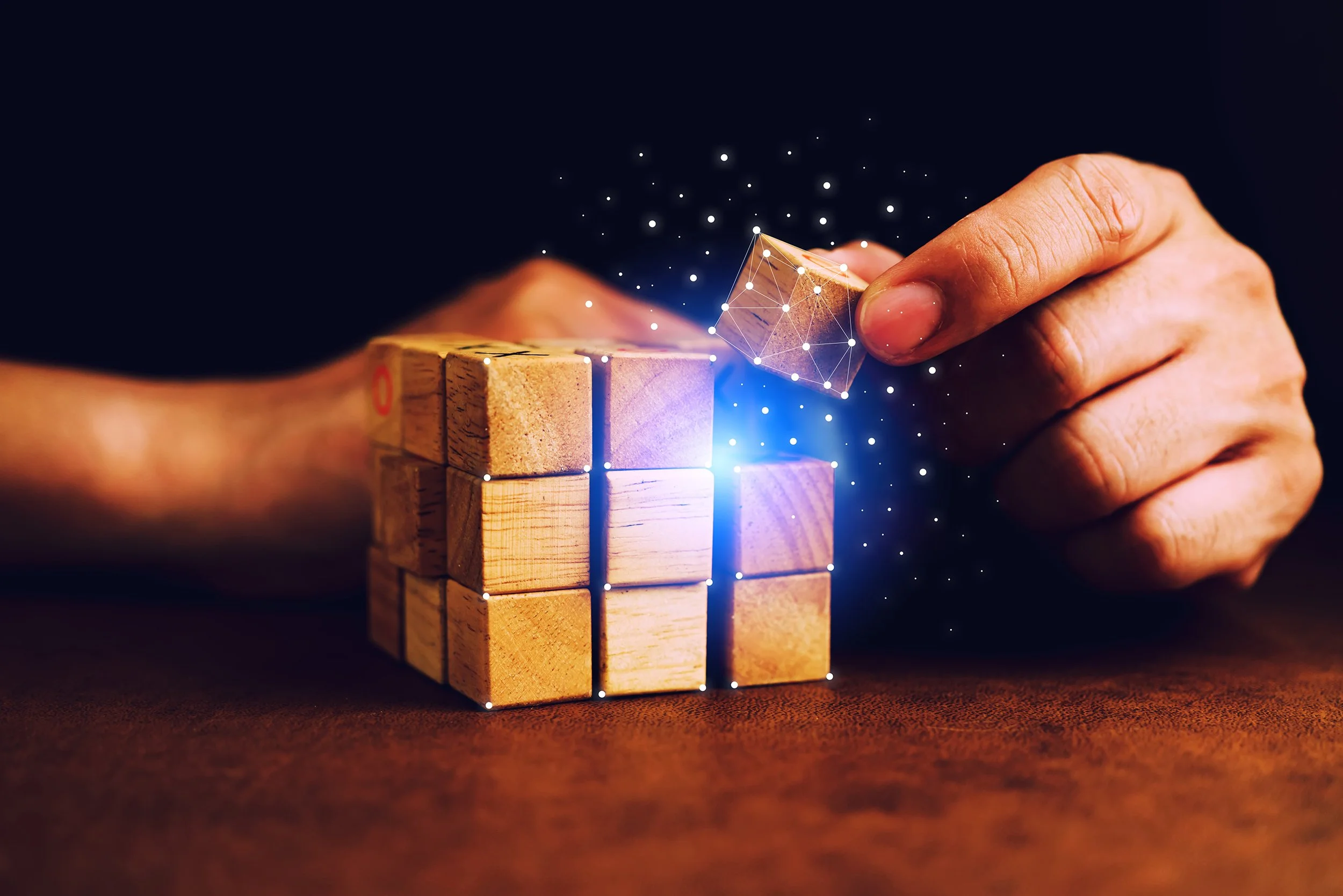 Close-up of a hand placing a piece in a colorful jigsaw puzzle on a table.