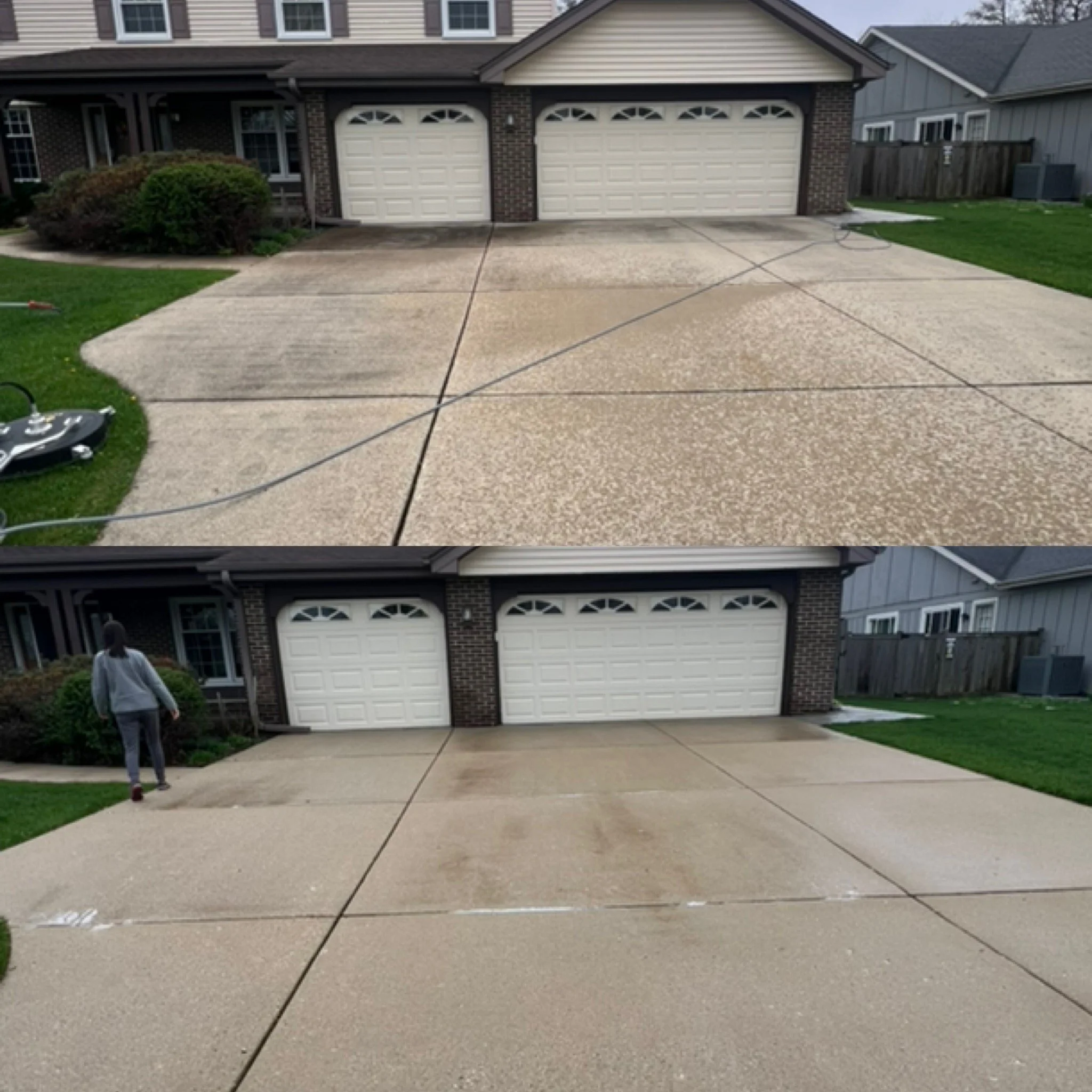 A suburban house with a two-car garage, a driveway, and a small front yard with bushes. There is a person standing near the bottom left corner of the image.