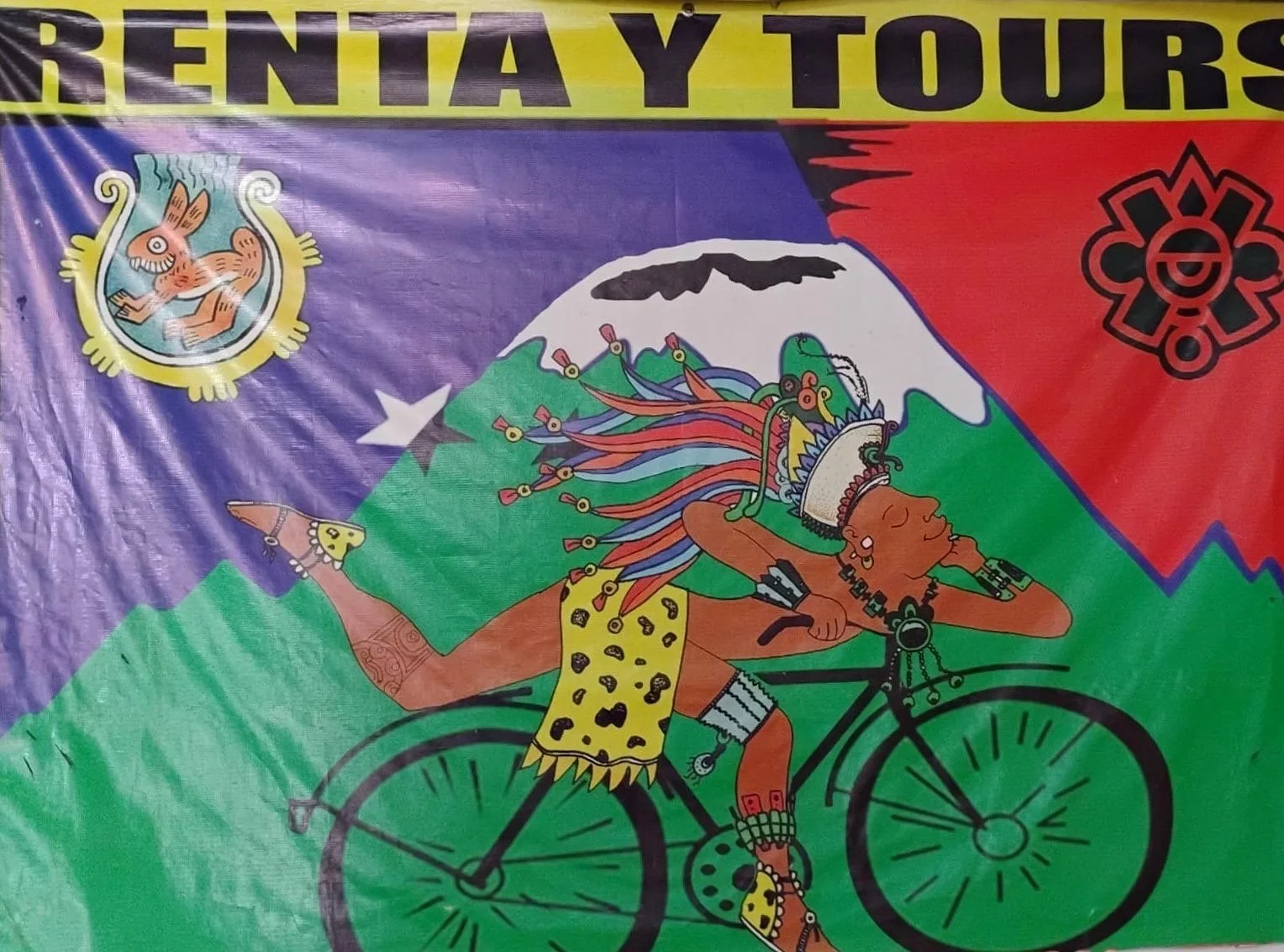Artistic depiction of a person in Aztec-style attire riding a bicycle in front of a mountain, with colorful feathers and patterns. The background includes various symbols and vibrant colors. The banner reads "RENTA Y TOURS."