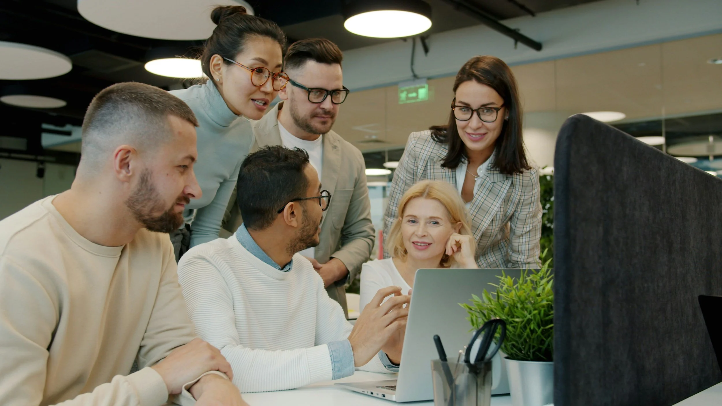 A group of business professionals collaborating around a computer screen during a QuickBooks bookkeeping coaching and training session
