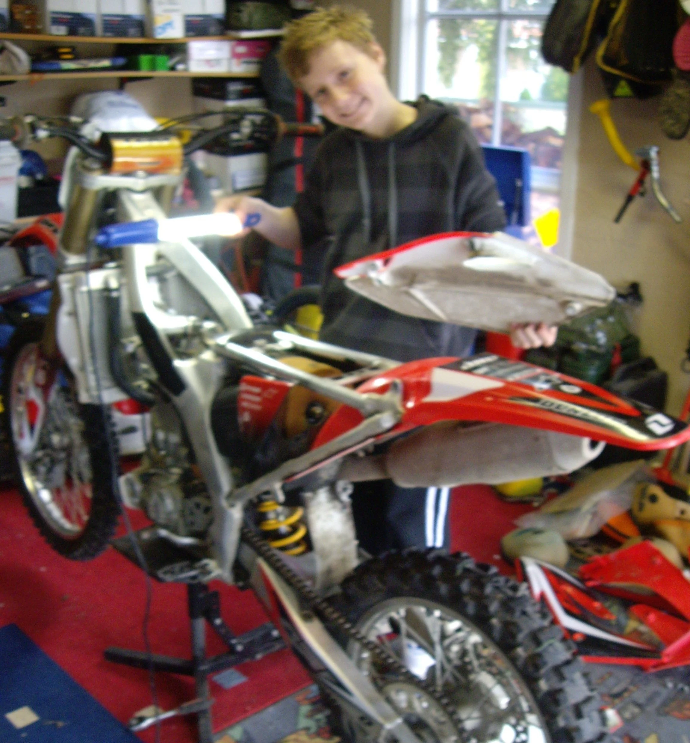 Teenager working on a dirt bike in a garage