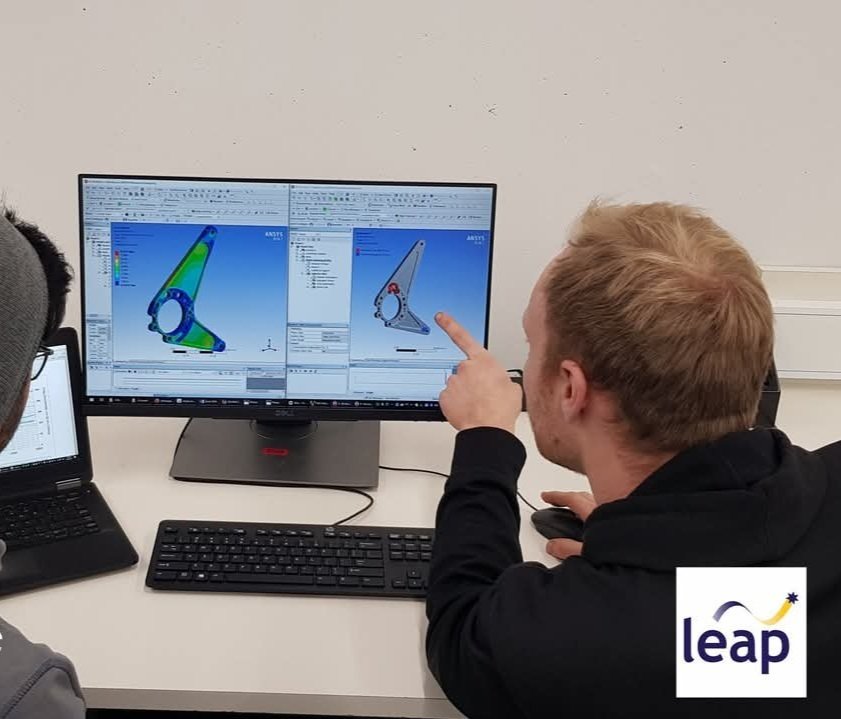 Two people analyzing engineering software on computer screens, focusing on a 3D model of a component, with "leap" logo visible.