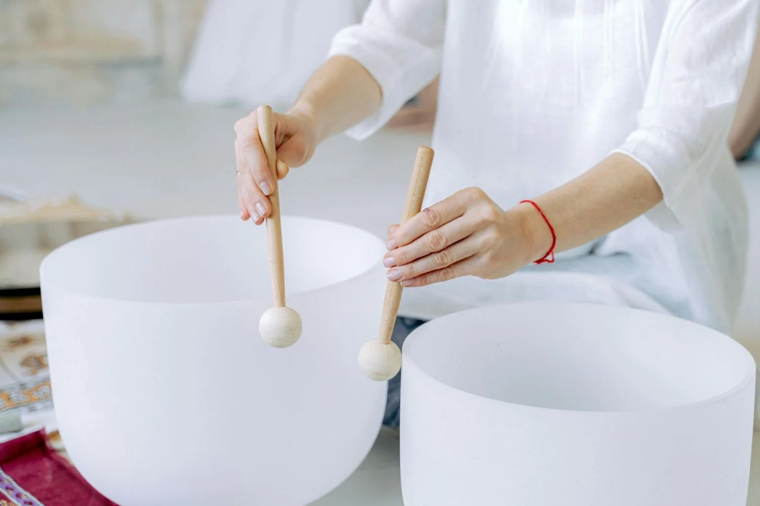 Person playing crystal singing bowls with mallets