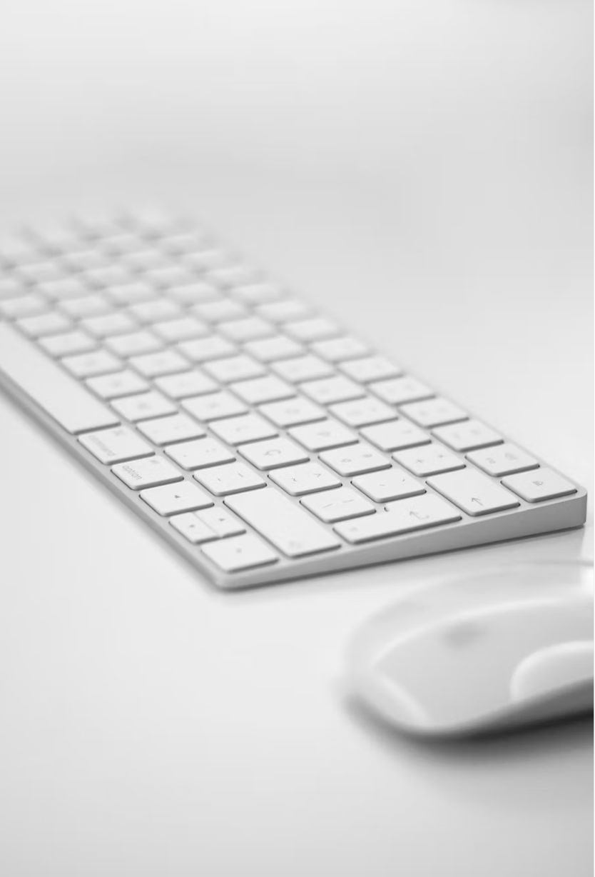 White wireless keyboard and mouse on a white desk.