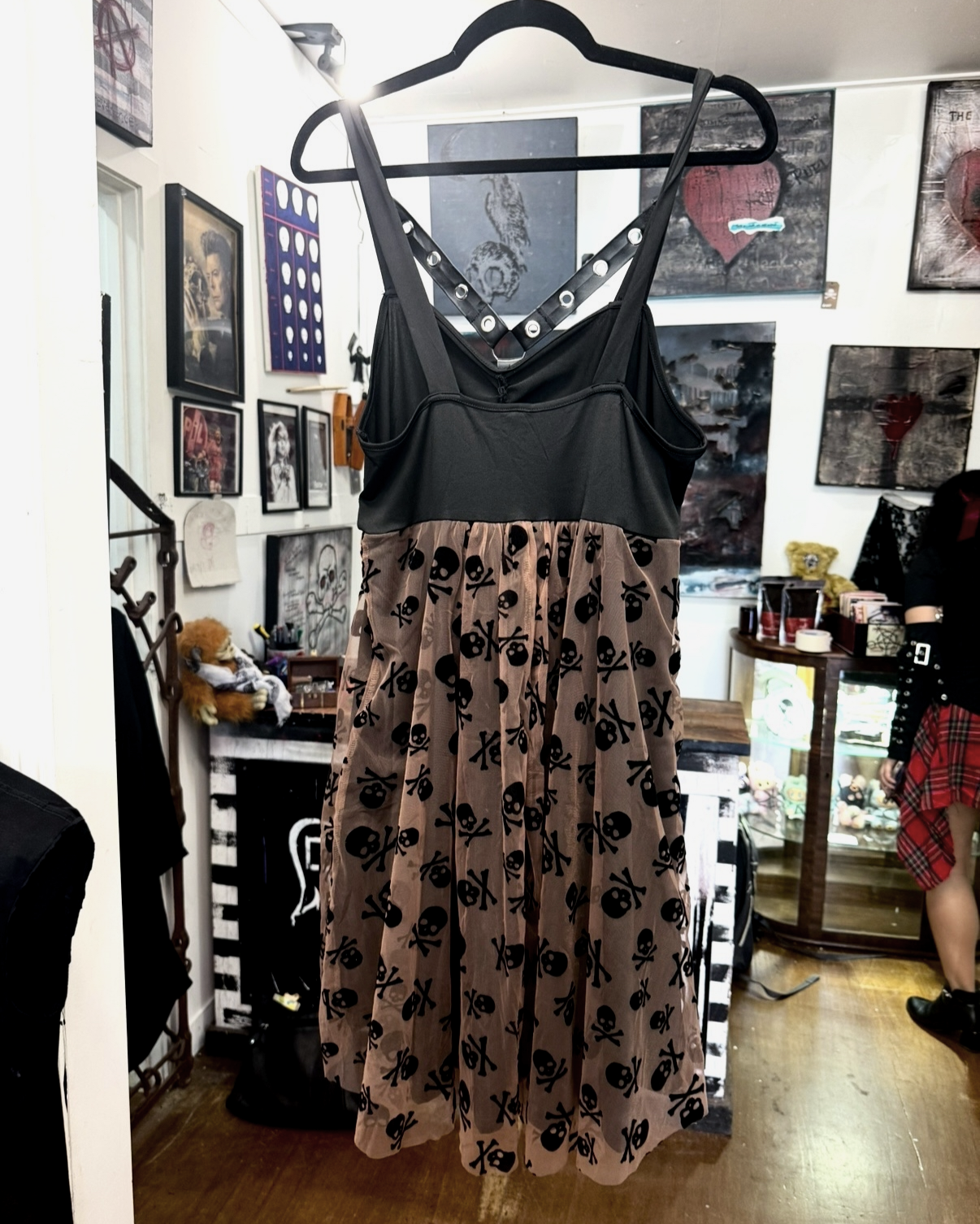 back of death by decaf dress with black straps that can be worn on shoulders or criss-crossed around neck with flowy coffee-coloured bottom adorned with little black skulls