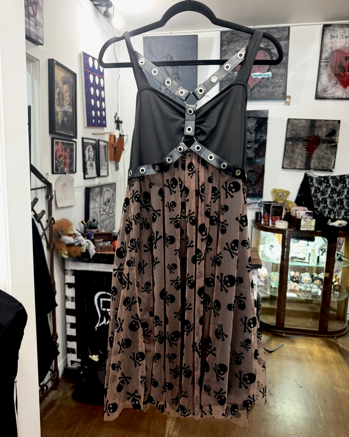 front of  death by decaf dress with black straps that can be worn on shoulders or criss-crossed around neck with flowy coffee-coloured bottom adorned with little black skulls