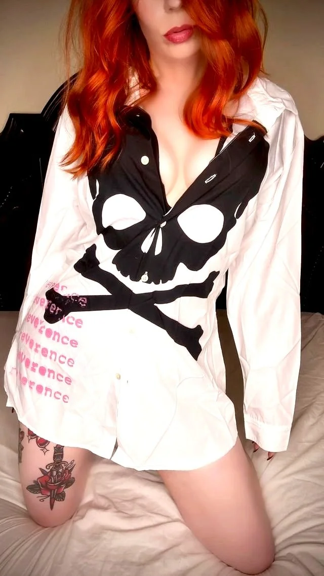 reverence delinquent white long-sleeved collared shirt with large black skull with pink "reverence" text on bottom repeated 3 times (front) worn by red-haired model