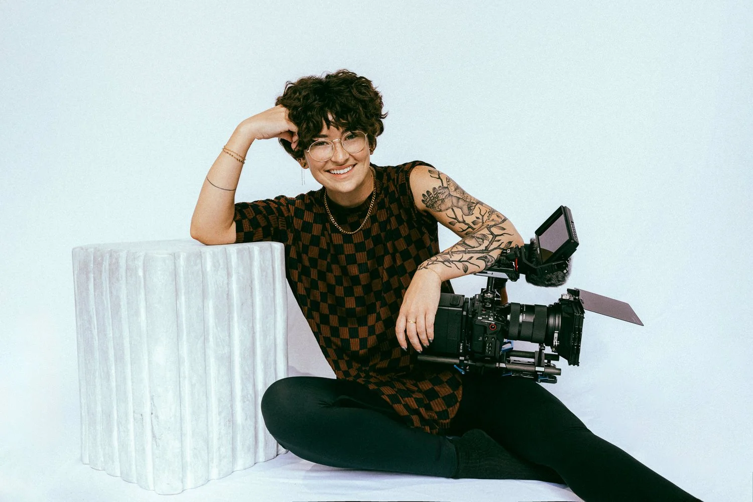 A woman in Seattle on a white backdrop, smiling and holding a cinema camera
