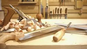 Woodworking workshop with hand tools, wood shavings, and a workbench.