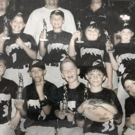 A youth football team posing with trophies and a fish, in black and white.