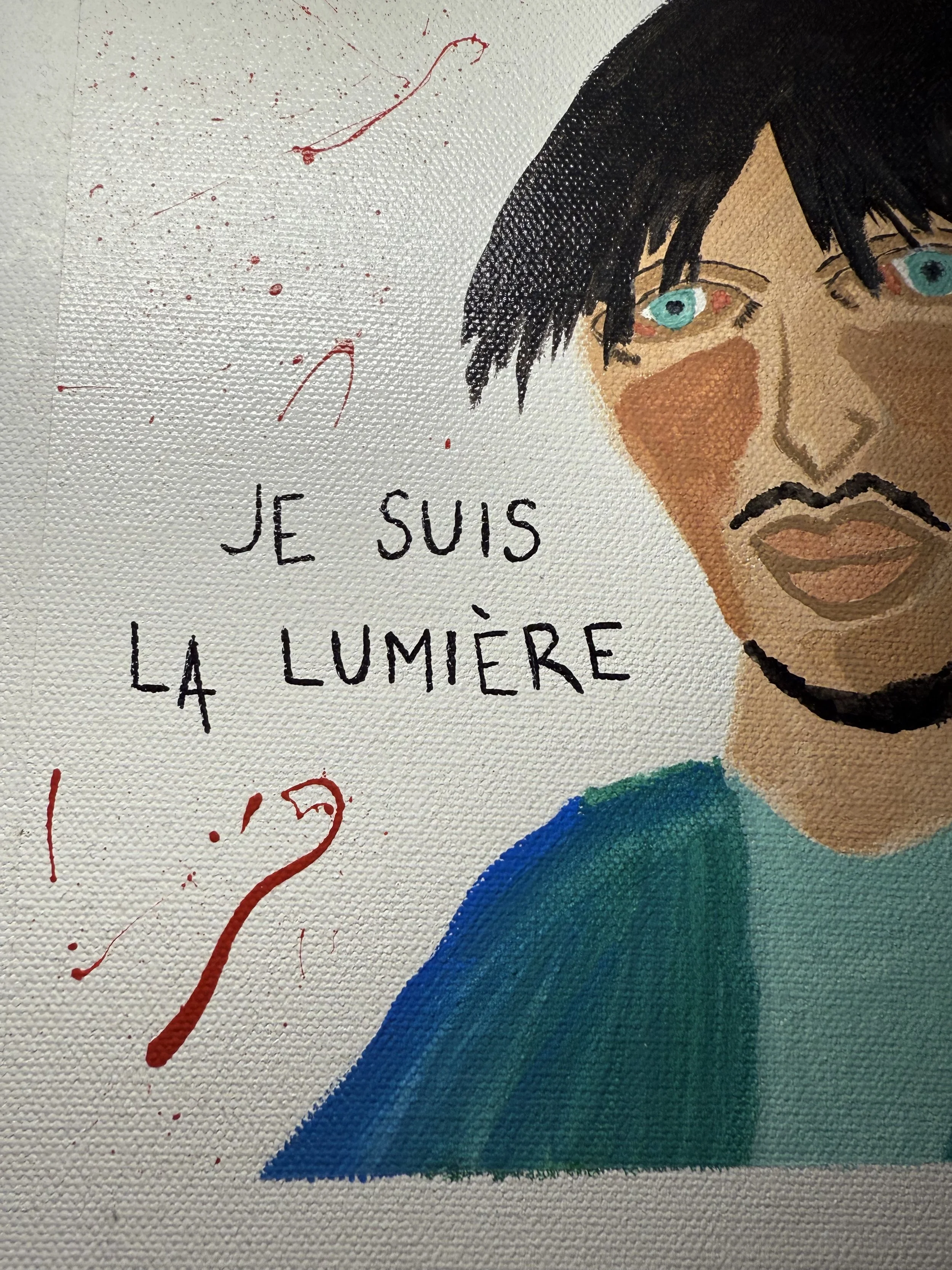 Close-up of a painting featuring a person's face with blue eyes and black hair, with red paint splatters and French text that reads "JE SUIS LA LUMIÈRE."