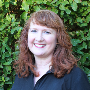 Woman smiling in front of green leafy background