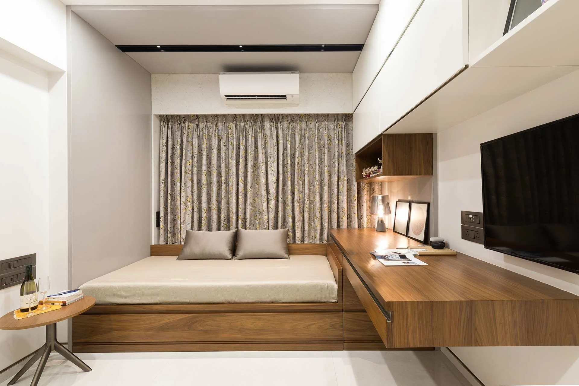 Modern hotel room with a bed, desk, TV, and window with curtains. In Mumbai photographed by Rishul Bangar, the best interior photographer.