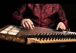 Person spielt ein Zither, das auf einem schwarzen Hintergrund liegt.