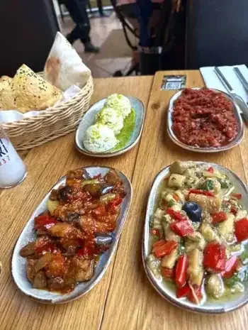 Verschiedene indische Gerichte auf Tellern, darunter Gemüsecurry, Fleischcurry, Salat, Papadum und Chutney.