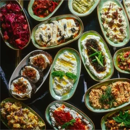 Meze in kleinen Schalen, die auf einem dunklen Tisch arrangiert sind.