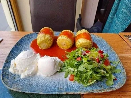 Gefüllte Paprika mit Salat, Quark und Tomatensauce auf einem blauen Teller
