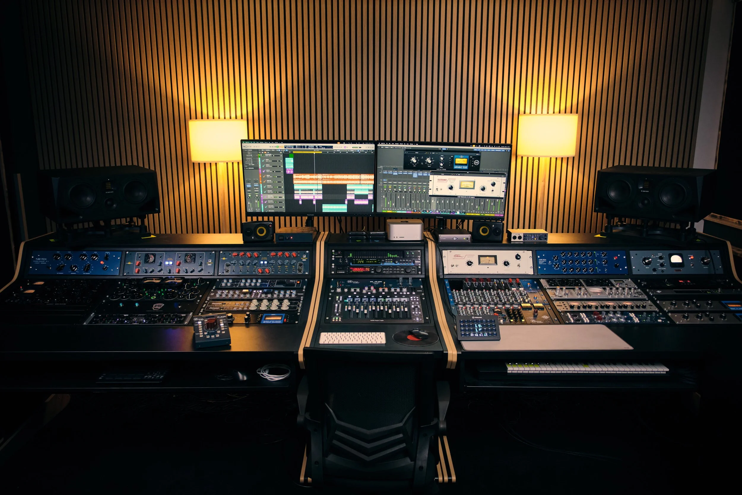 A professional music studio with mixing console and various audio equipment.