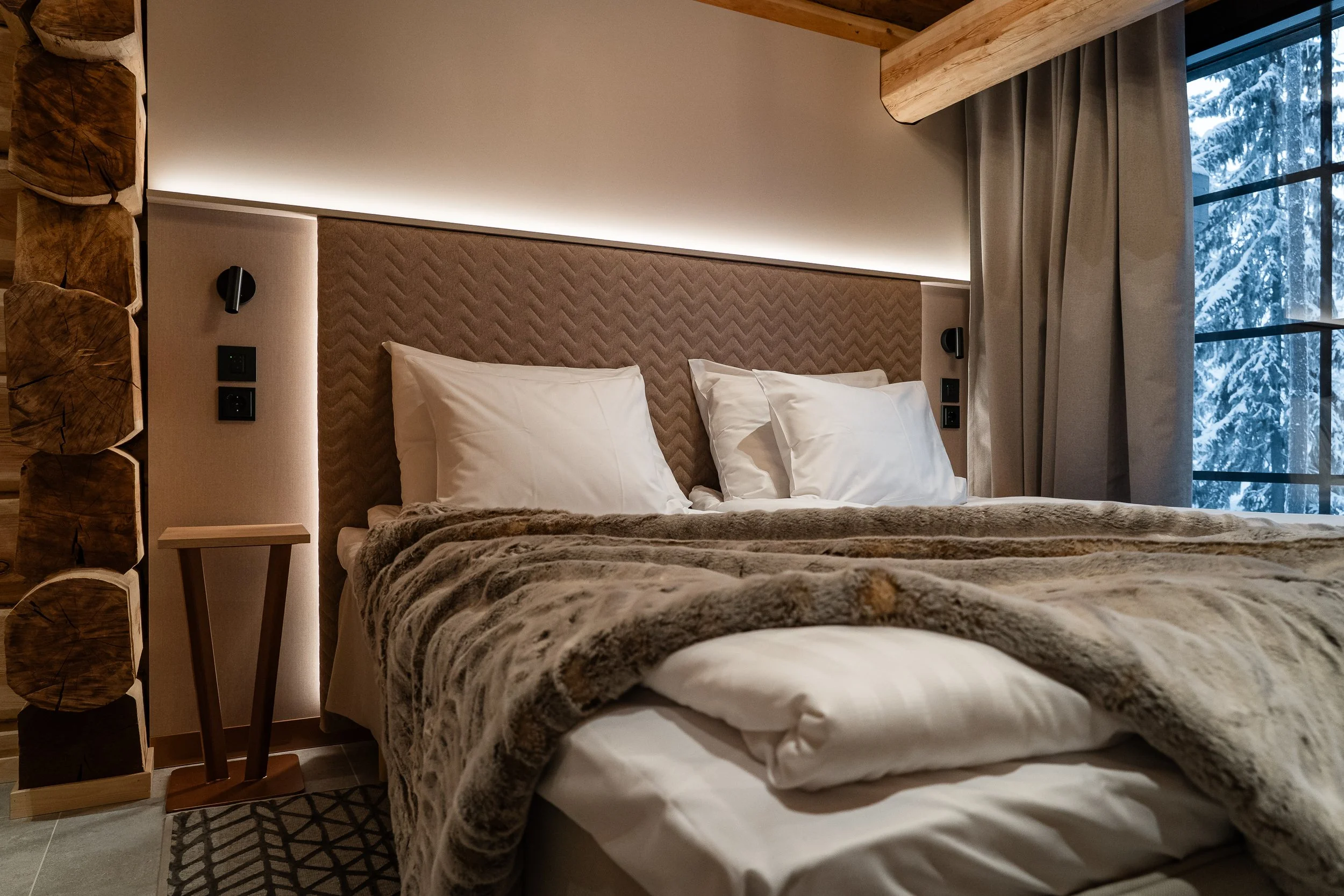 Väsyttävä hotellisänky pehmeillä tyynyillä, vilpoisalta ikkunalta näkyy luminen talvimaisema.