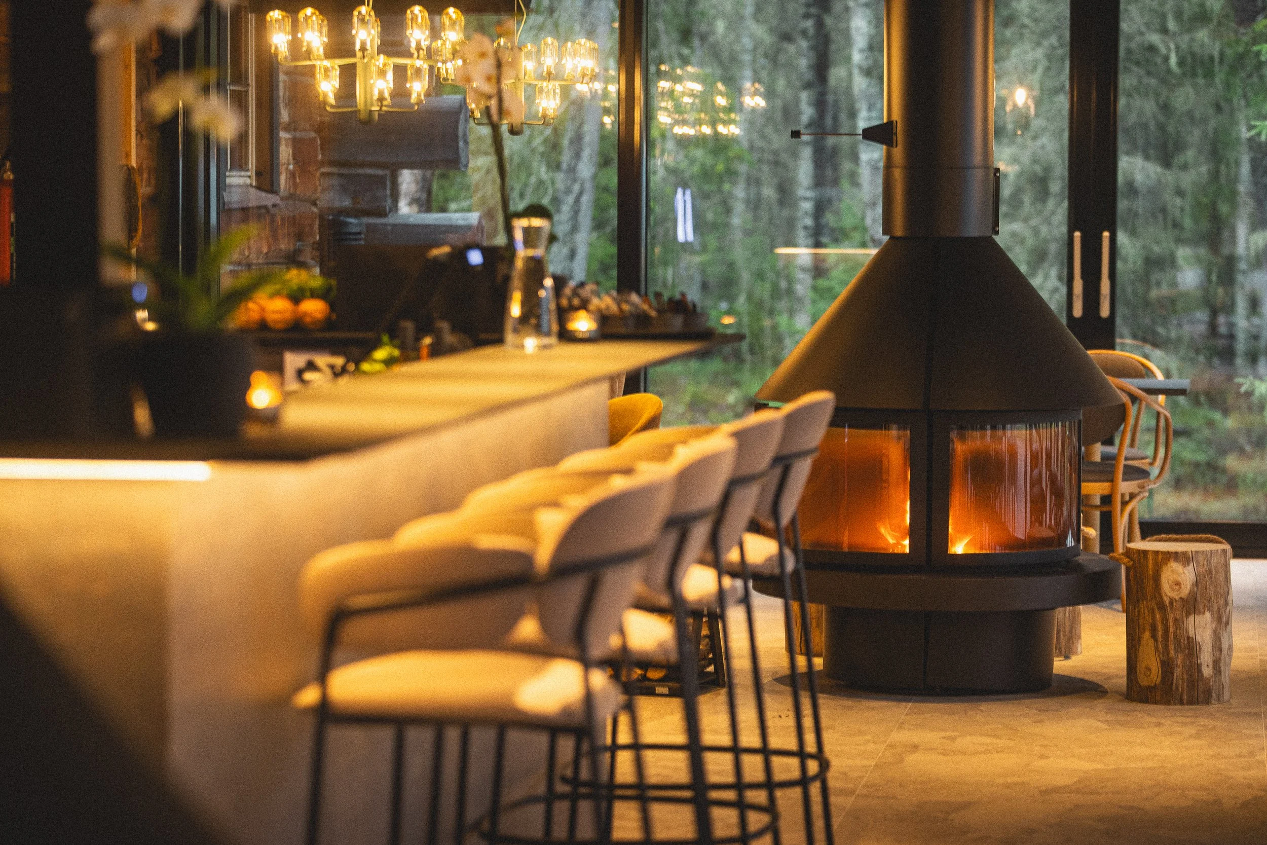 Lämmitetty tulitikku ja tyhjiä sävyjä keittiösaarekkeen ympärillä ja takan edessä. Tunnelmallinen sisustus, jossa luonnonläheiset materiaalit ja modernit valaisimet.