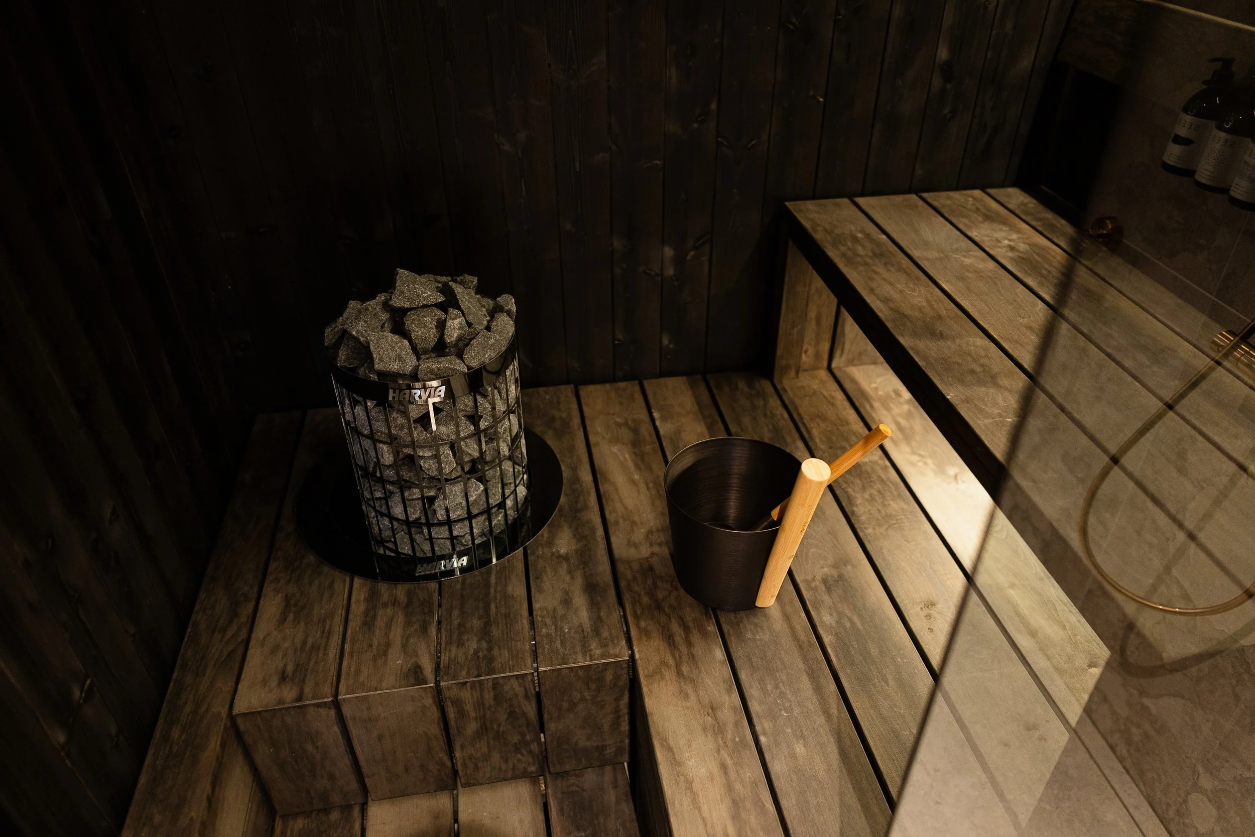 Savu ja kiviastia saunassa, ympäröivä puupaneeli ja lattia.