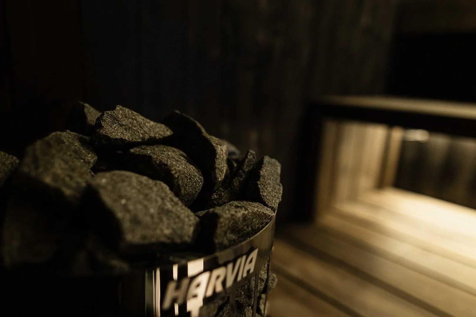 Lämmitin kuumaankivillä sauna- tai höyryhuoneessa, jossa on savusauni. Kuvassa on kiviä ja lauteita.