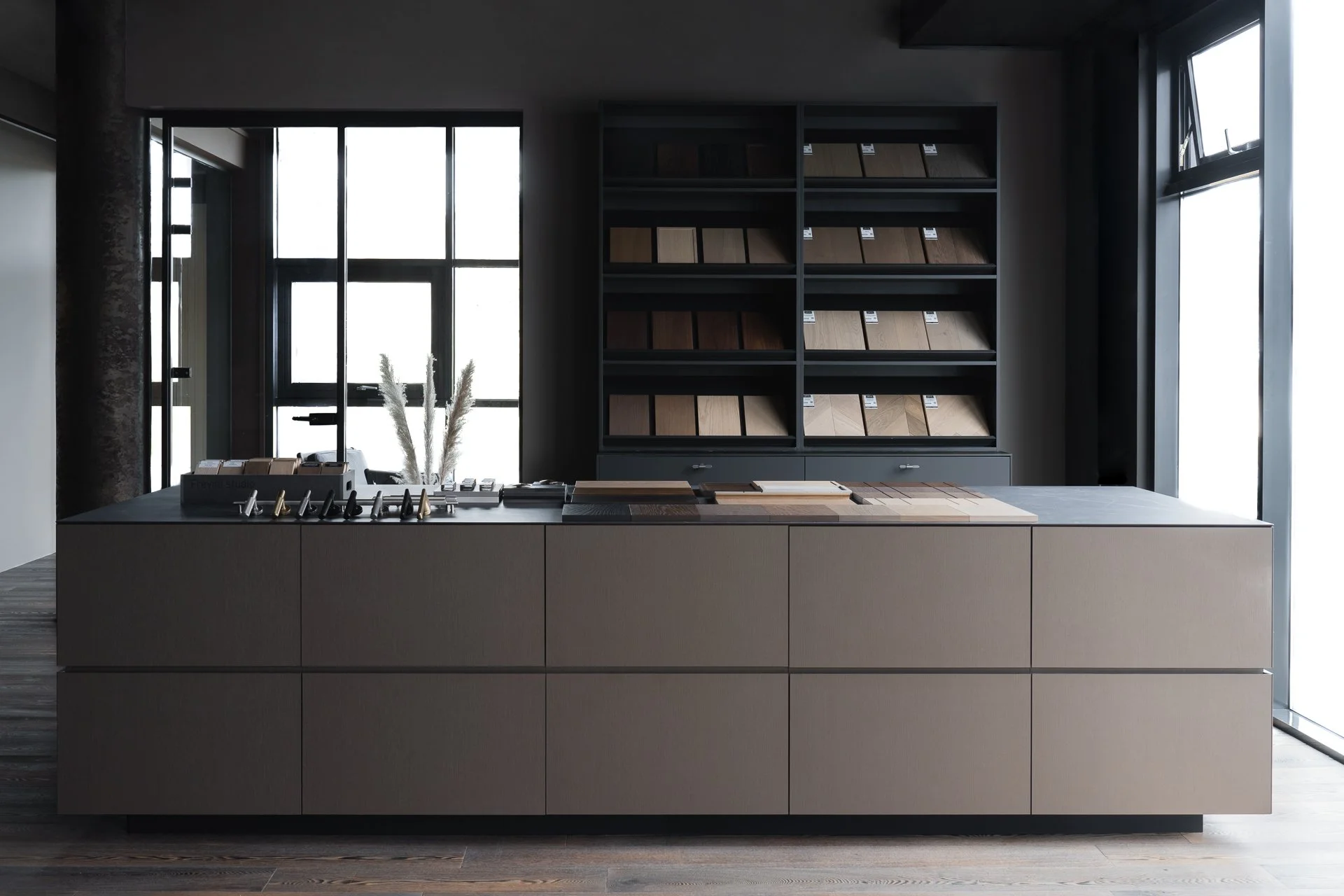 Display of wood flooring samples on a table in a showroom with large windows in the background.