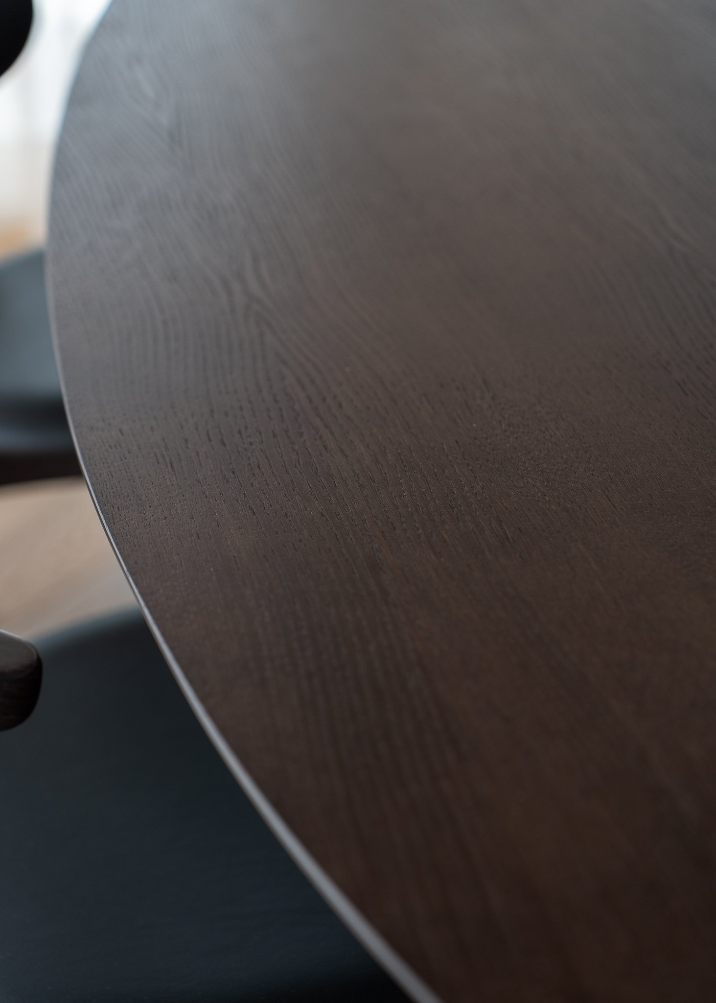 Close-up of a darkwood table with visible grain, with a blurred background.